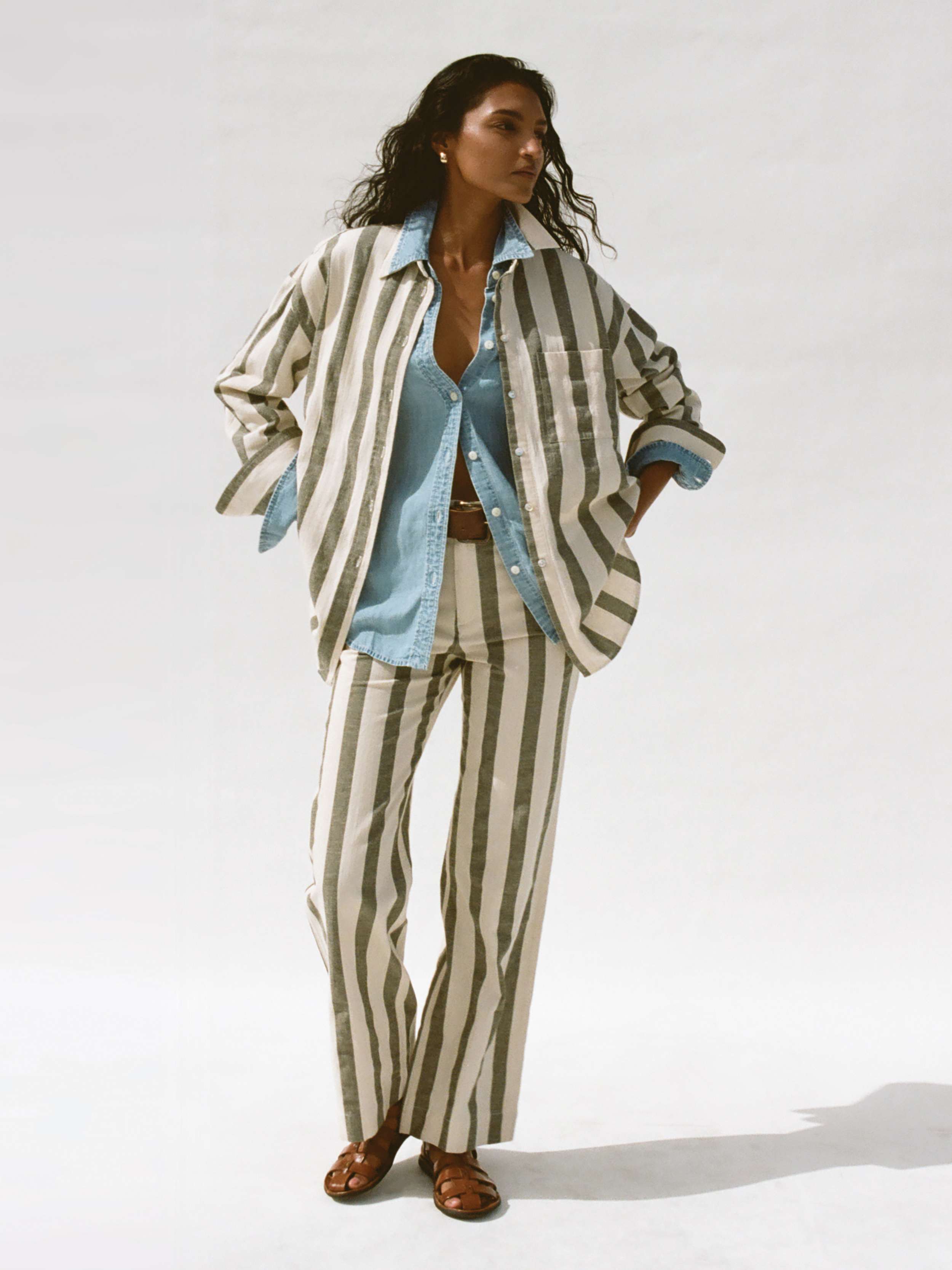 Woman wearing a green and white striped jacket with matching pant against a background