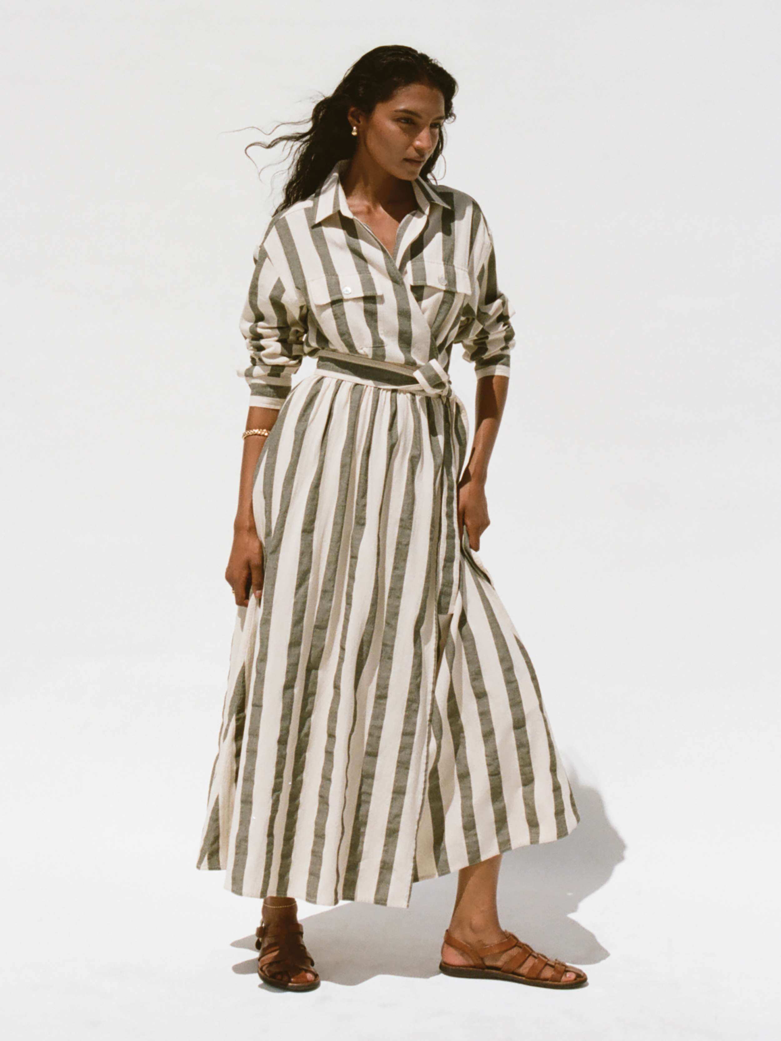Woman wearing a green and white striped wrap dress against a white background