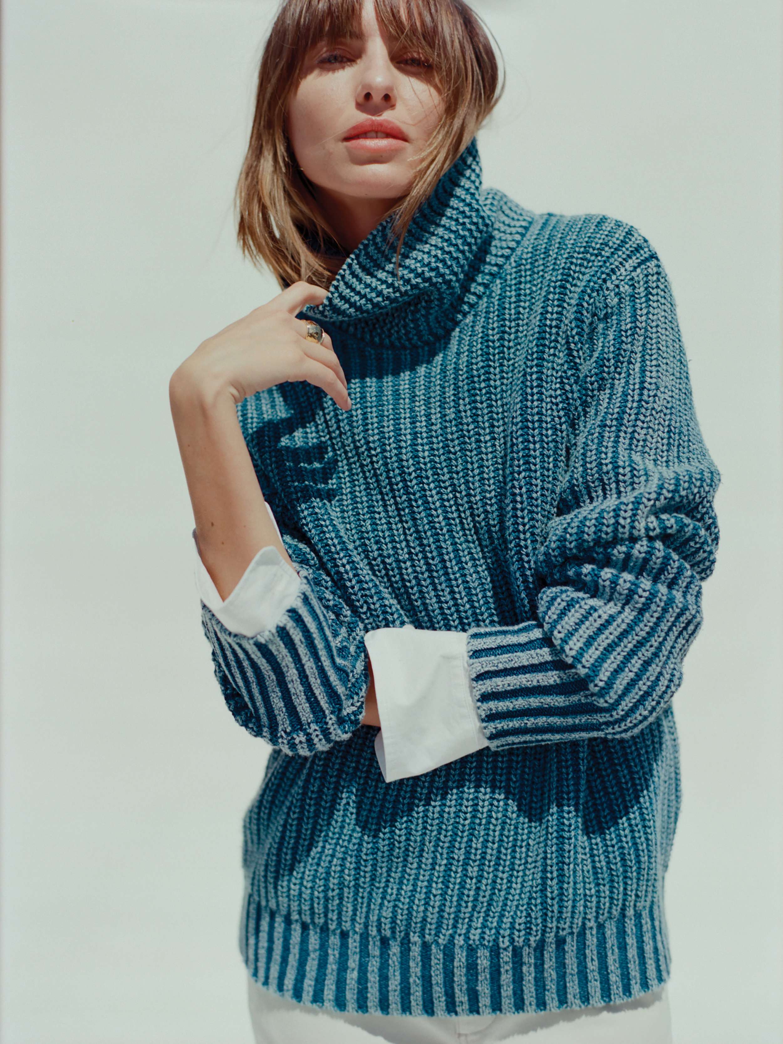 Woman wearing a blue knitted sweater against a white background
