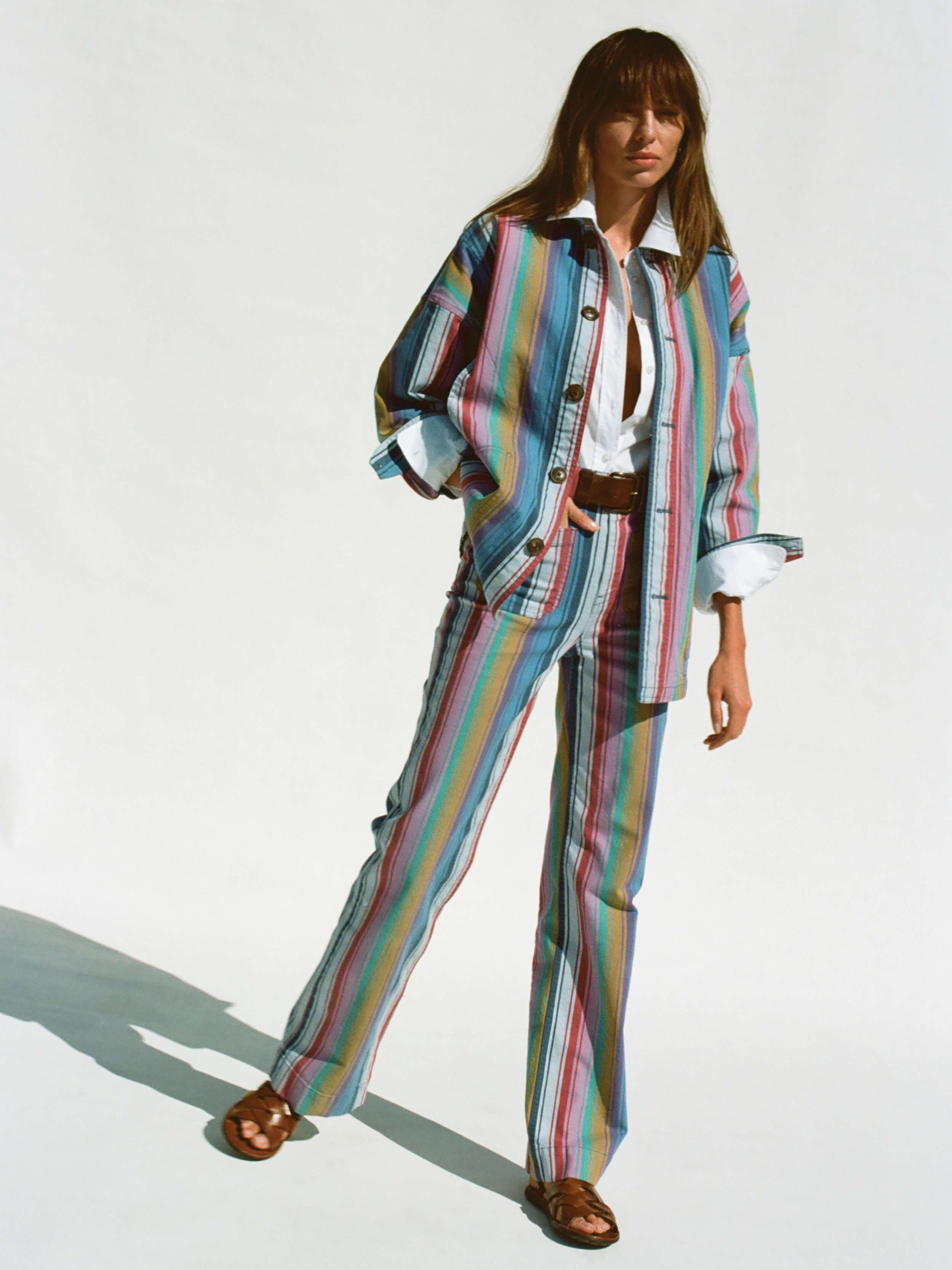 Woman wearing a multicolor striped jacket and matching pants against a white background