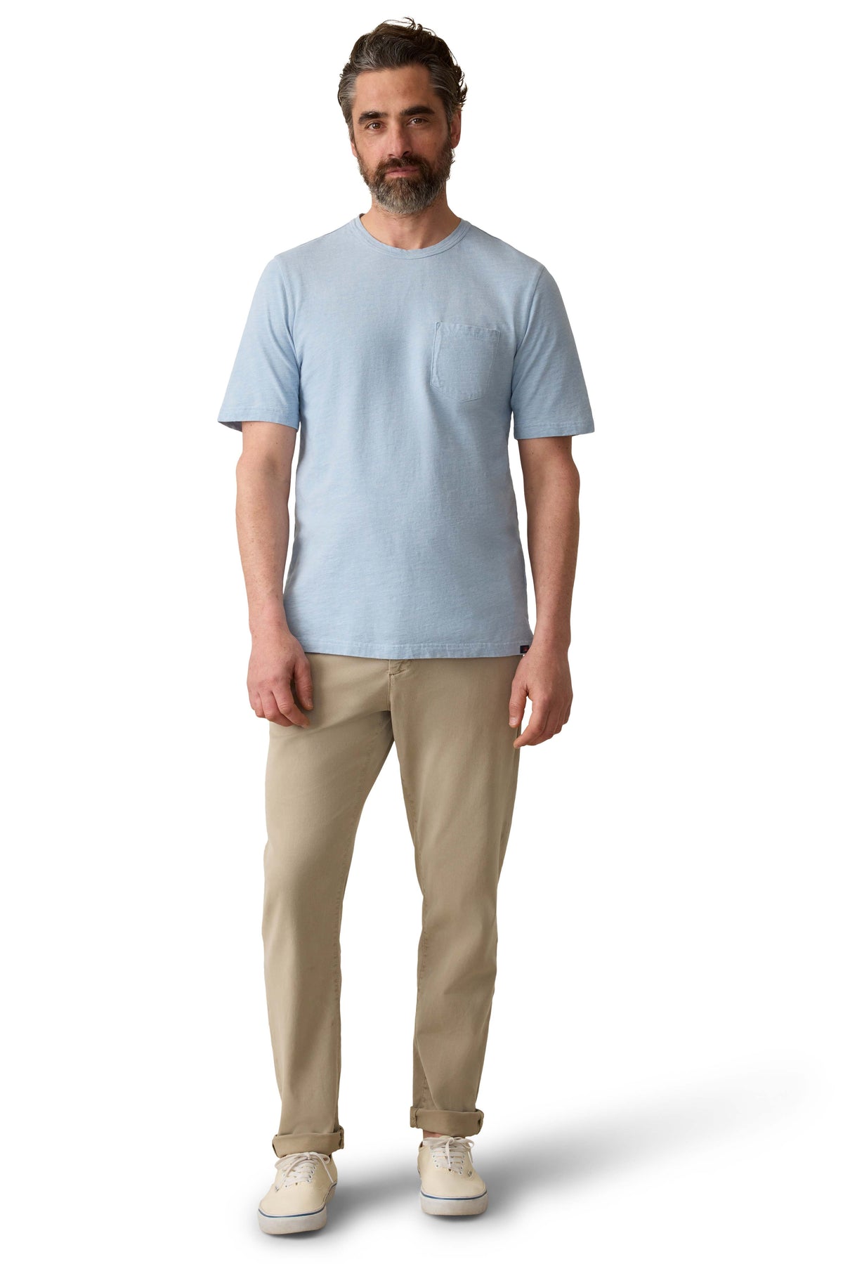 A man wearing a blue tee, beige pants, and sneakers, image 2 of 3