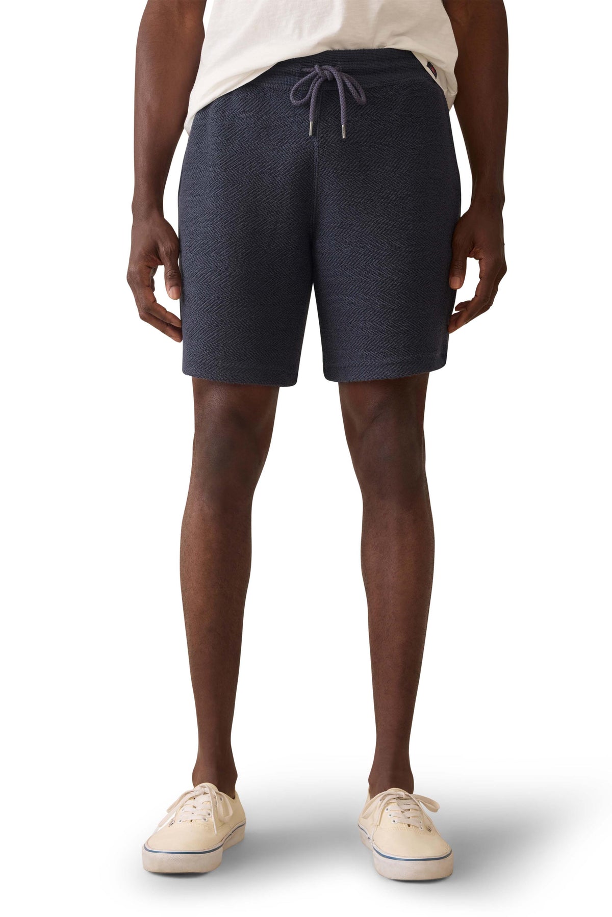 A man wearing navy sweat shorts and a white t-shirt, image 2 of 3
