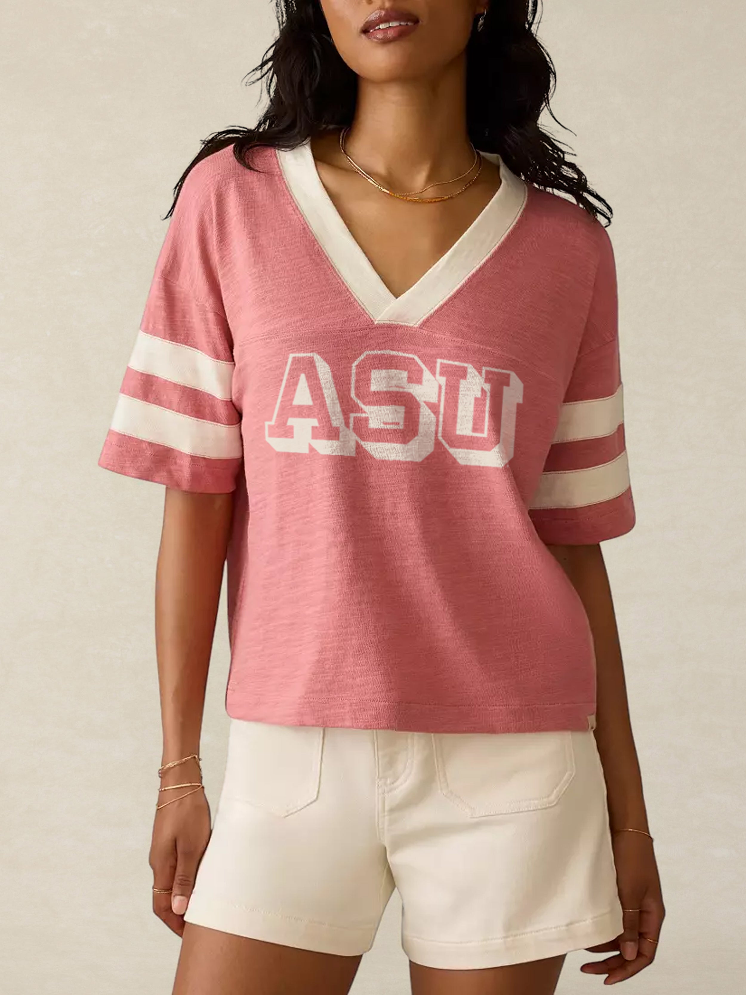 Woman wearing a pink Arizona State University shirt with a graphic on the center chest against a beige background