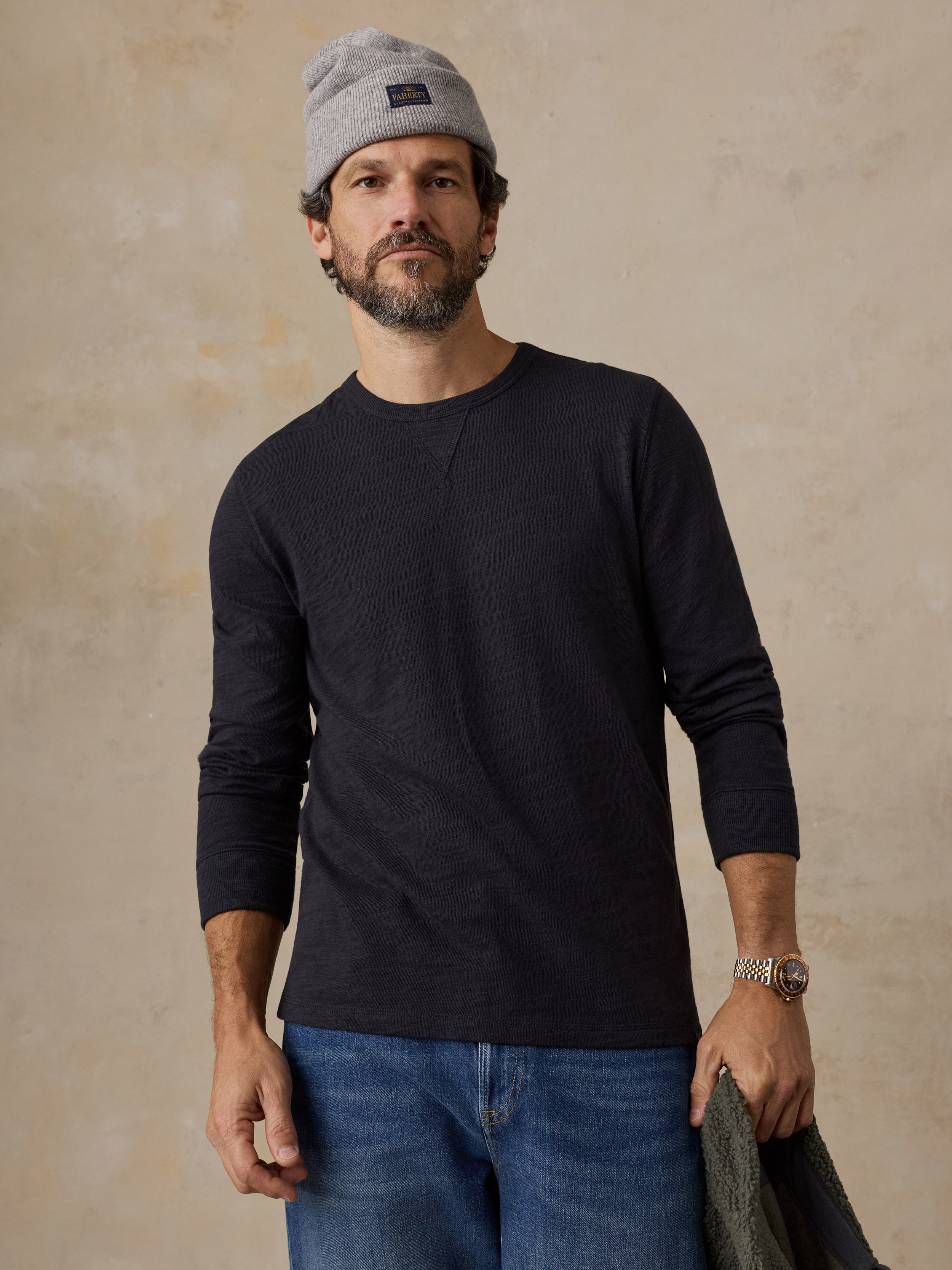A man wearing a black crewneck and a beanie