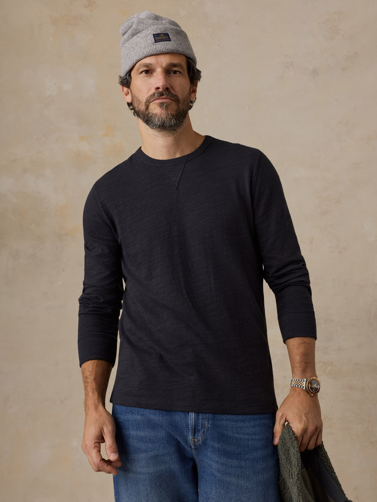 A man wearing a black crewneck and a beanie, image 1 of 6