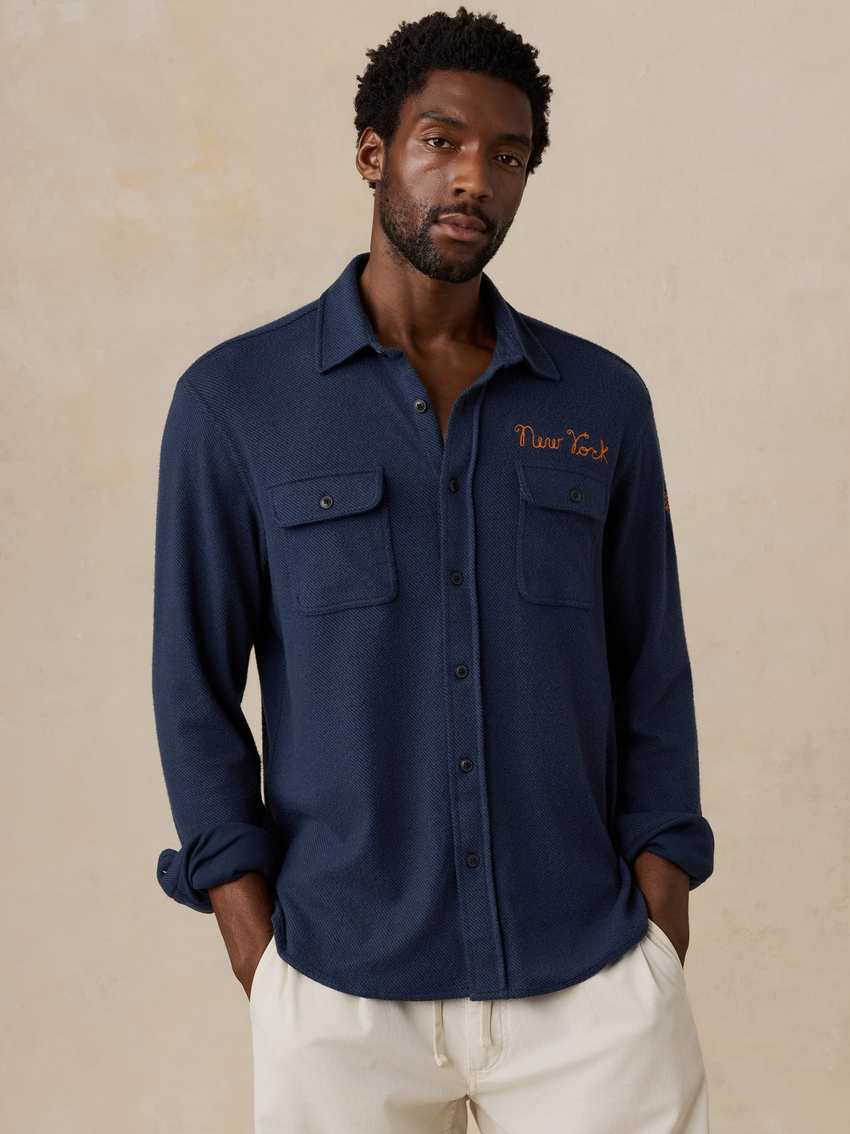 A man wearing a navy NY Knicks button up shirt, image 1 of 6
