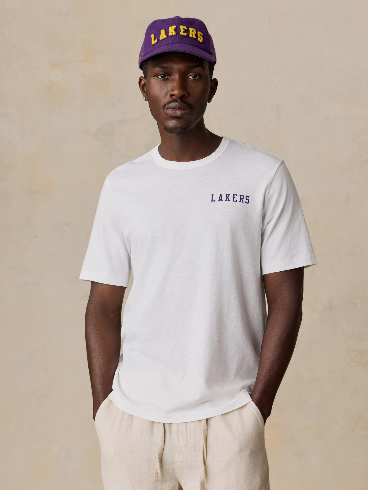 A man wearing a white LA Lakers tee and hat, image 2 of 6