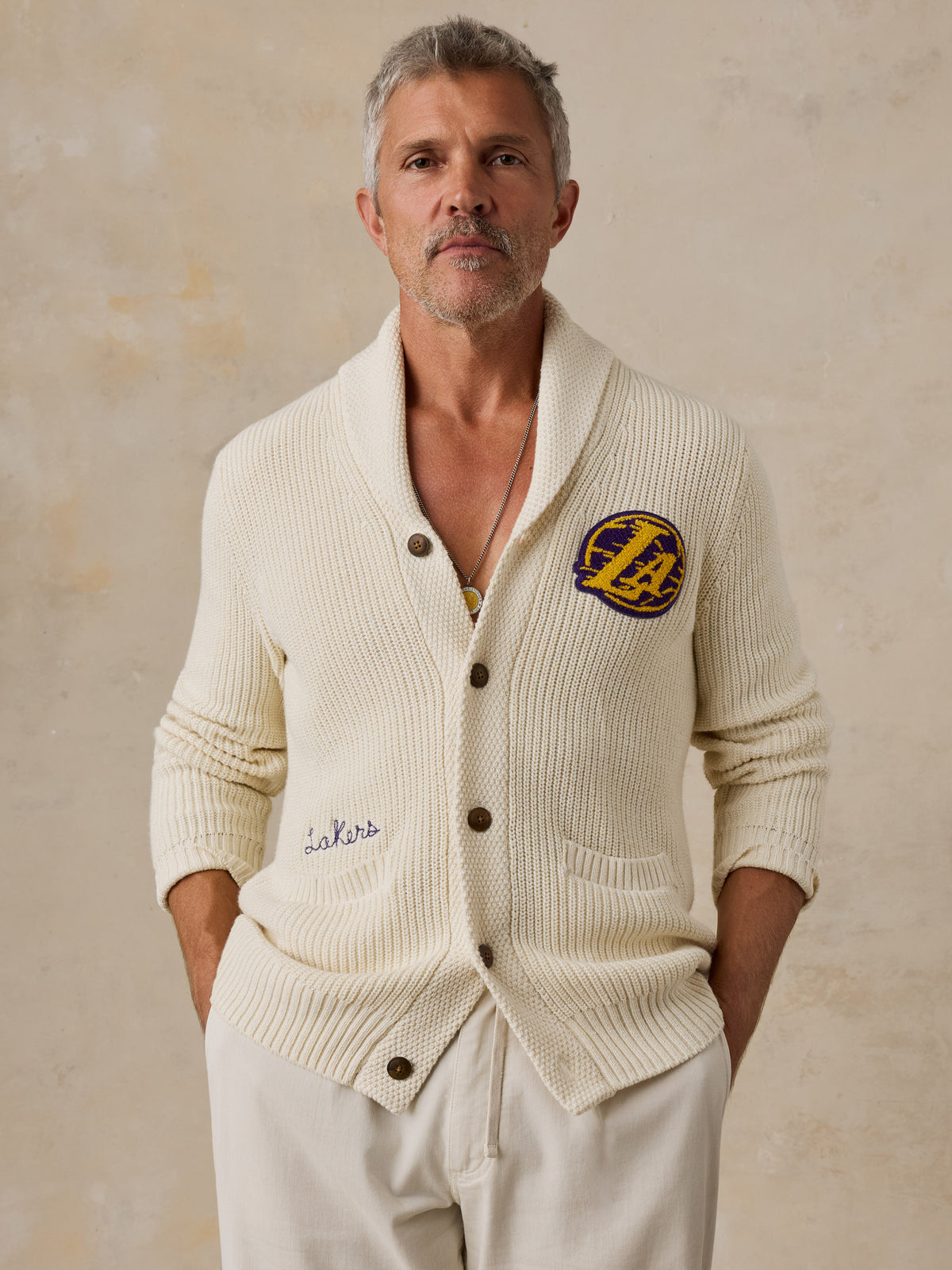 A man wearing an off-white LA Lakers cardigan and white pants, image 1 of 7
