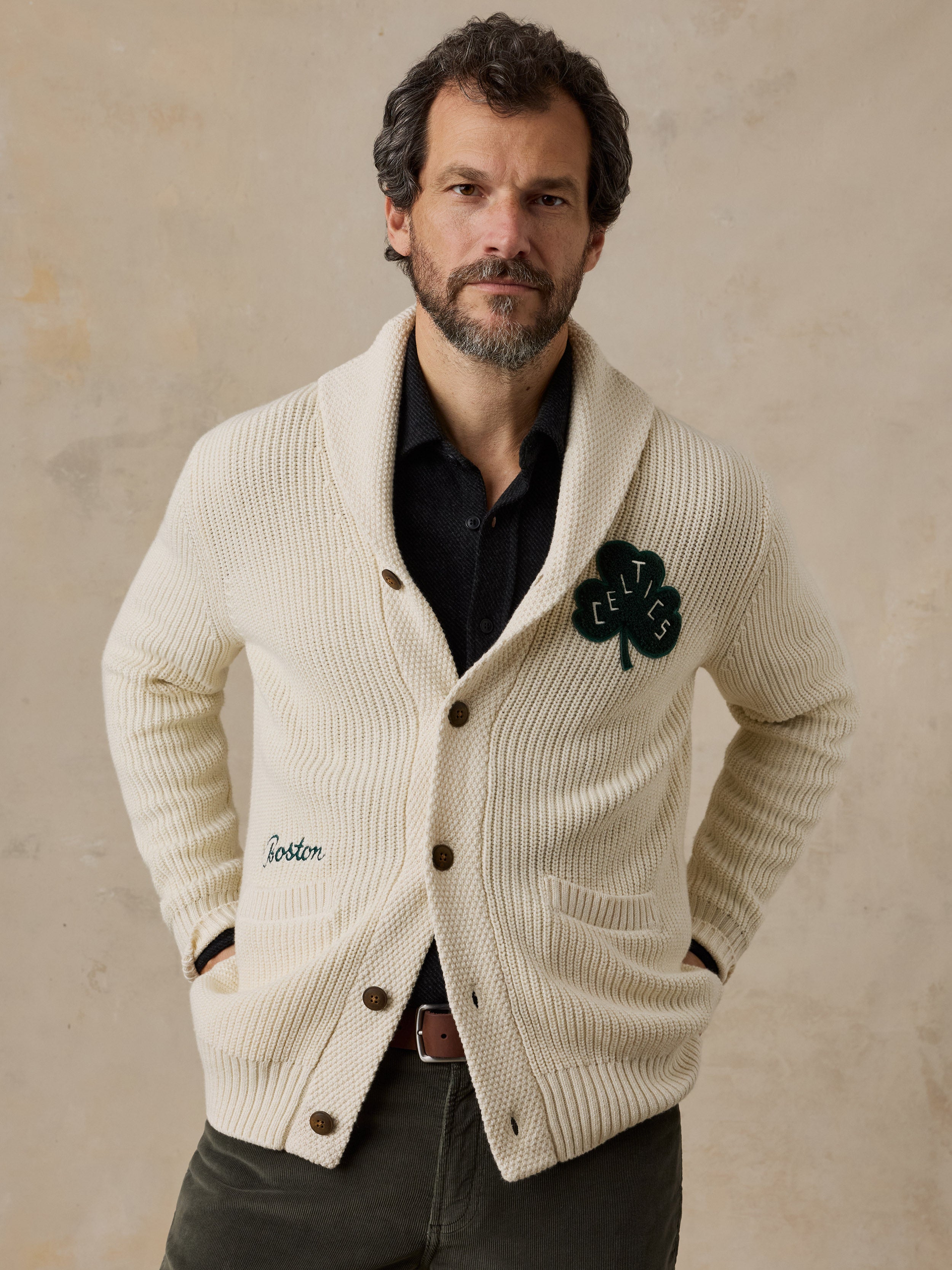 A man wearing an off-white Boston Celtics cardigan and green pants