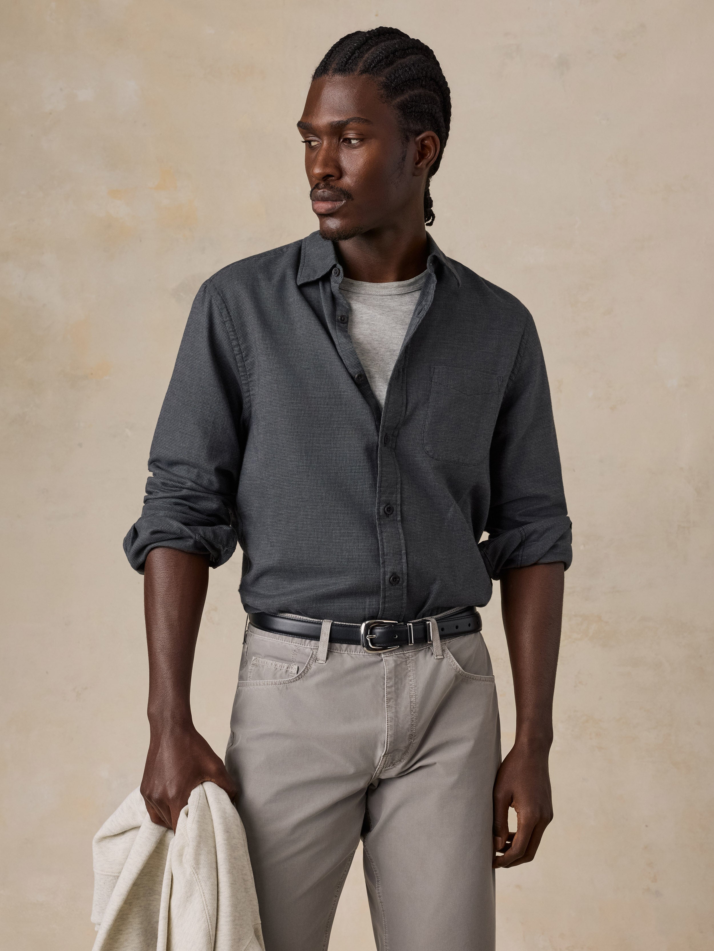 A man wearing a dark grey button down shirt and grey pants