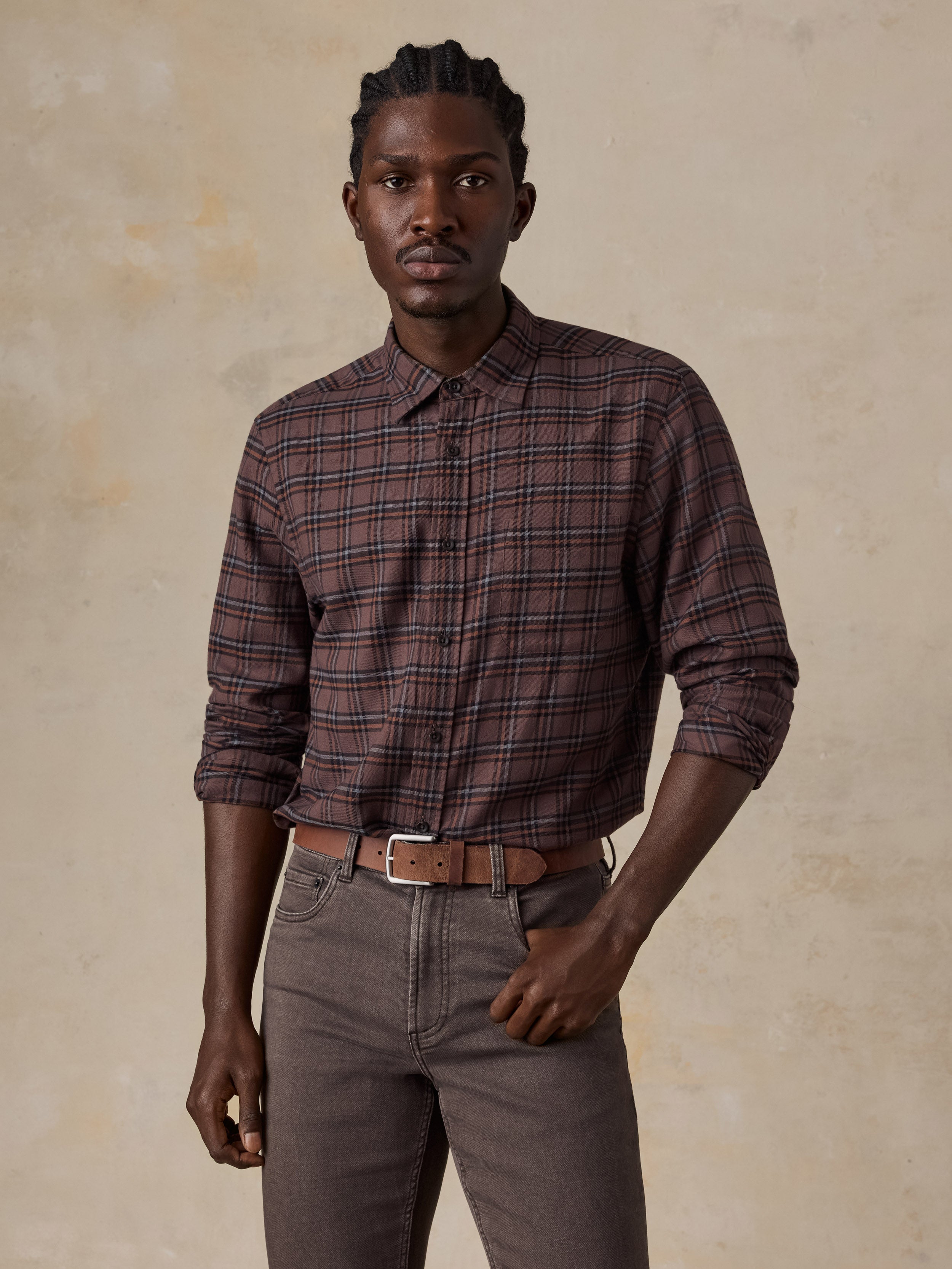 A man wearing a red plaid shirt and brown pants