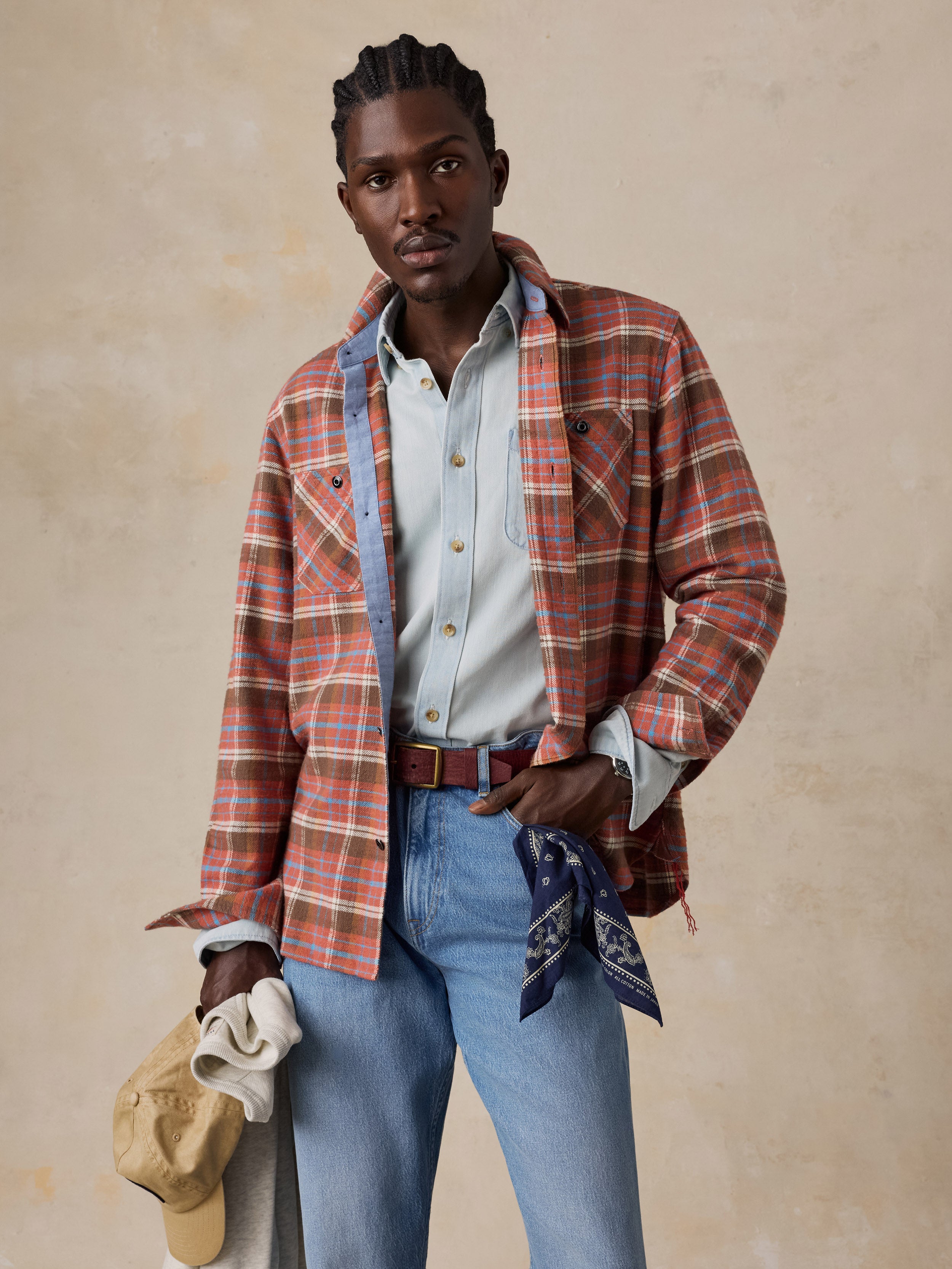 A man wearing a red plaid flannel over a chambray shirt and blue jeans