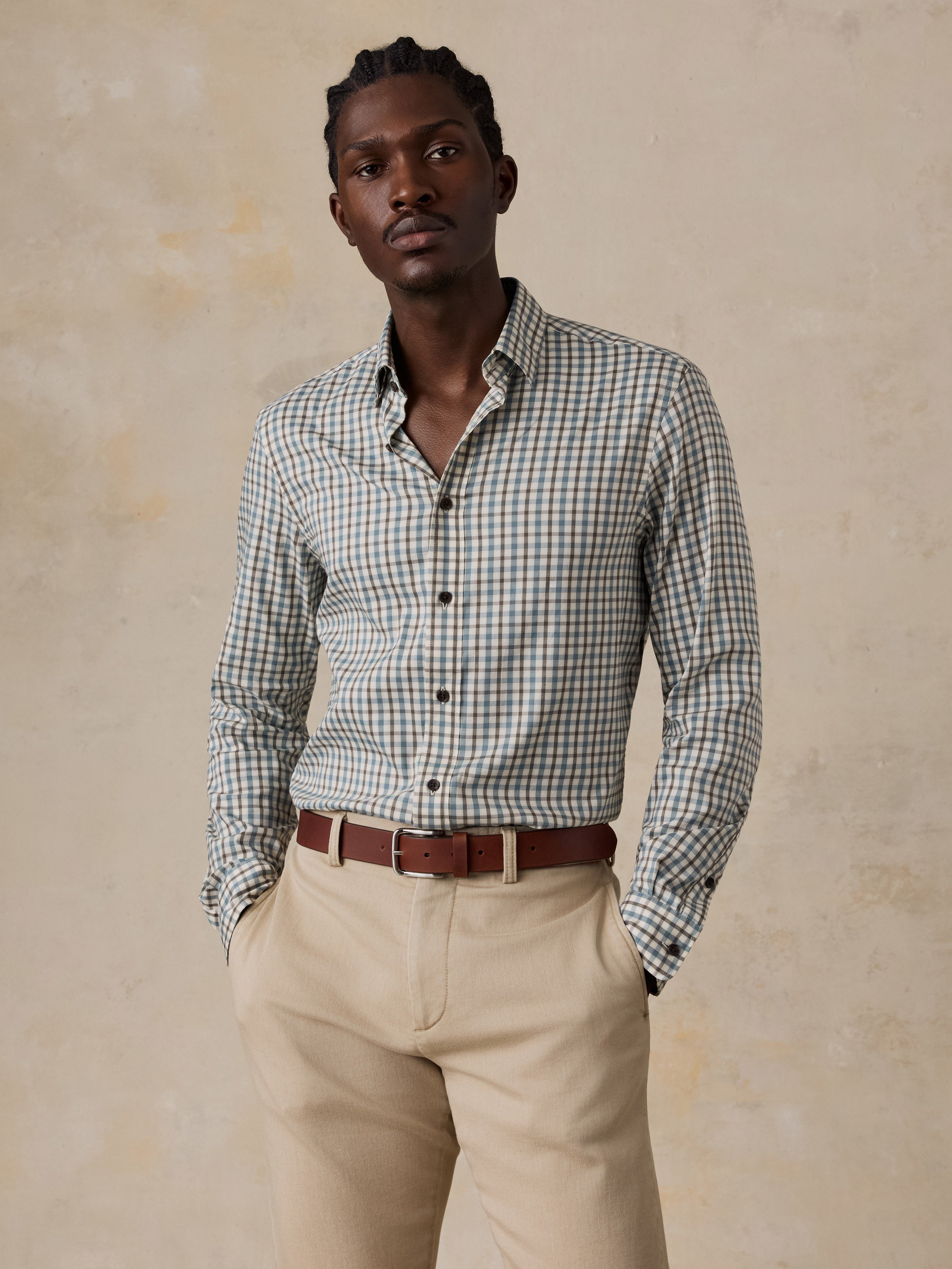 A man wearing a plaid shirt and beige pants