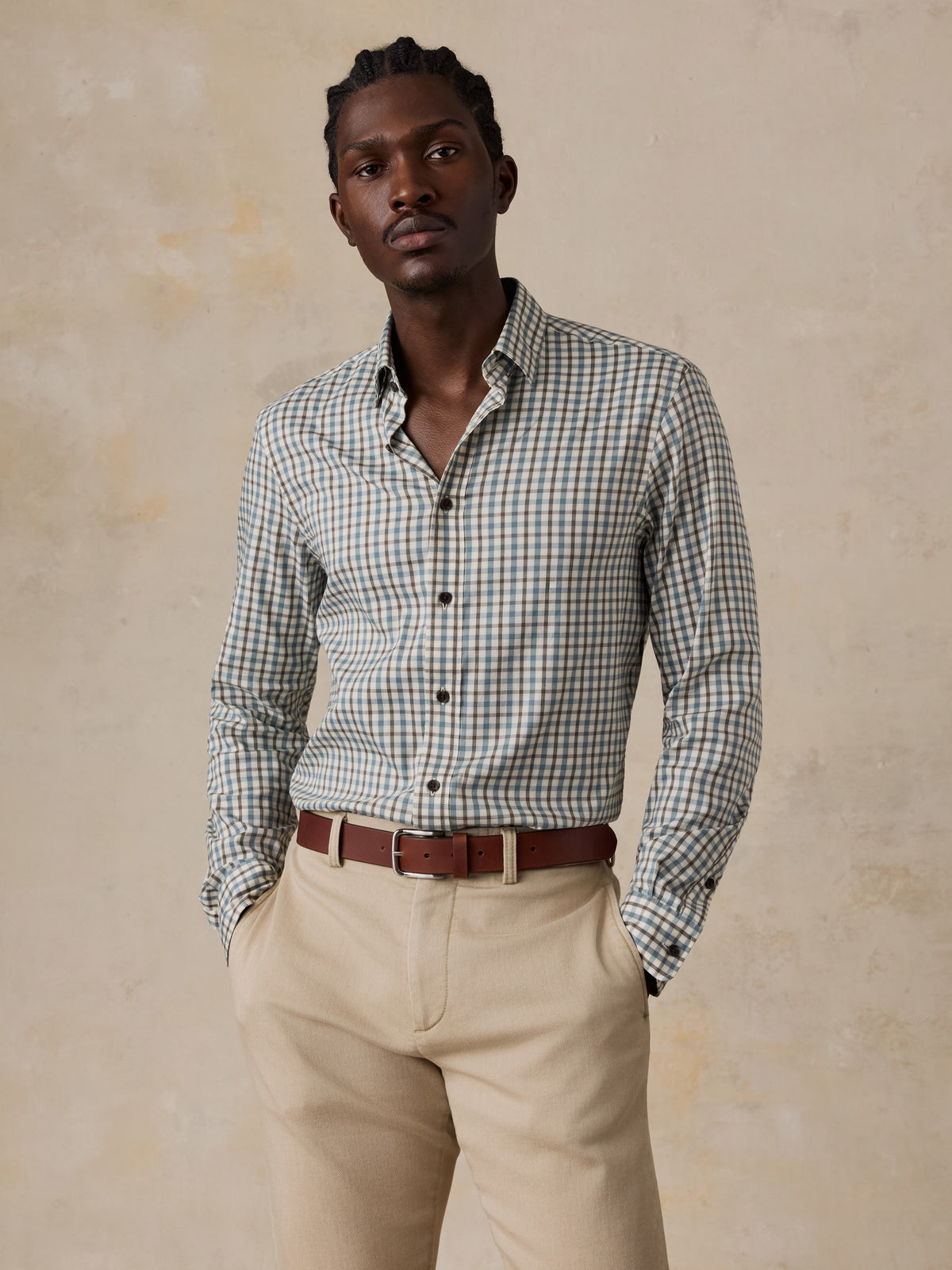 A man wearing a plaid shirt and beige pants, image 1 of 5