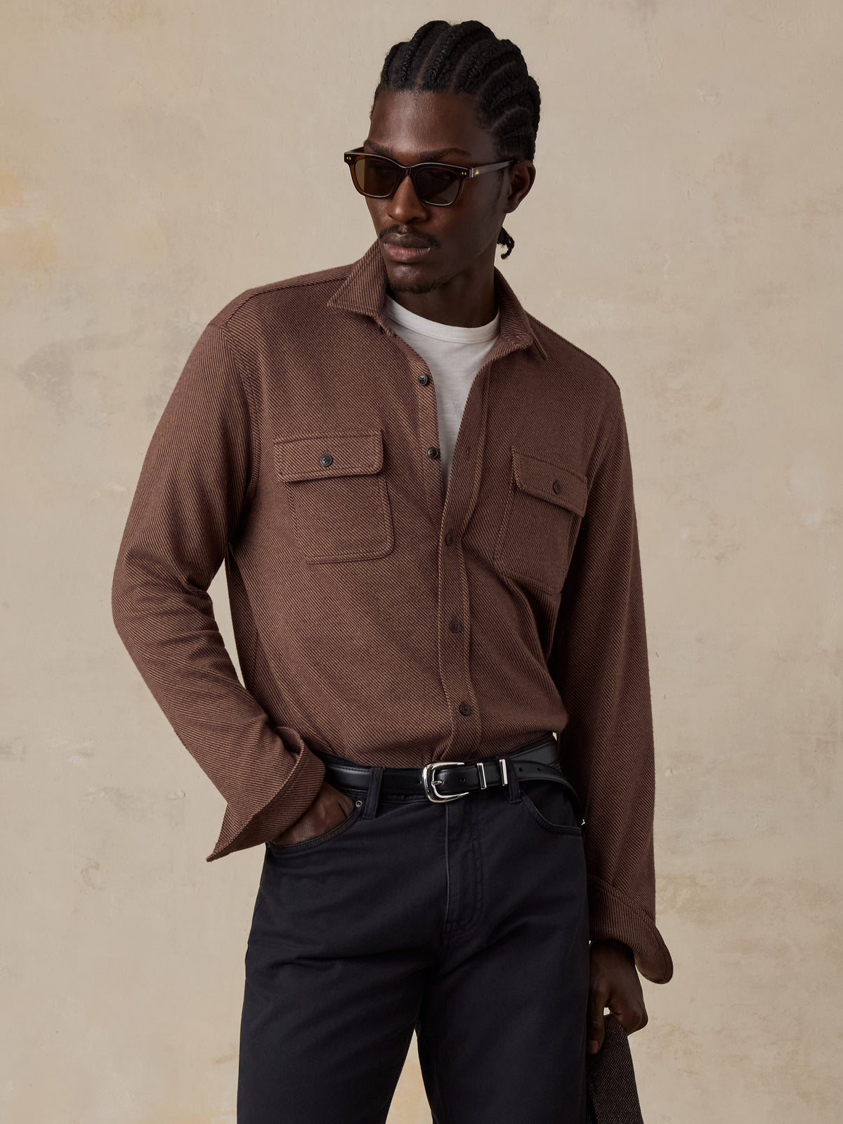 A man wearing a brown shirt and black pants, image 1 of 5
