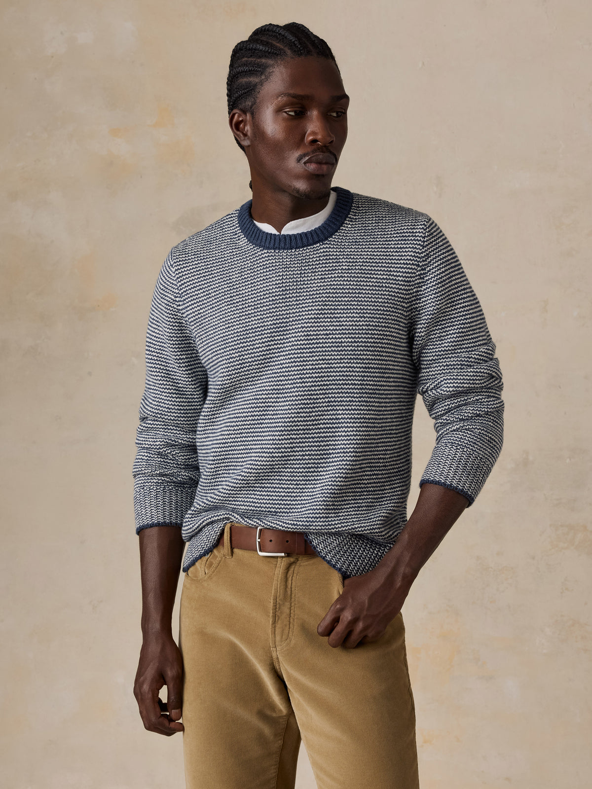 A man wearing a blue striped sweater and tan corduroy pants, image 1 of 5