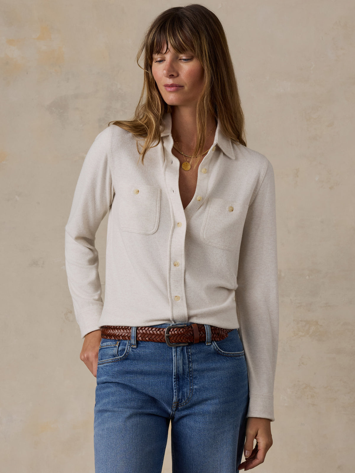 A woman wearing a white shirt and blue jeans, image 1 of 7