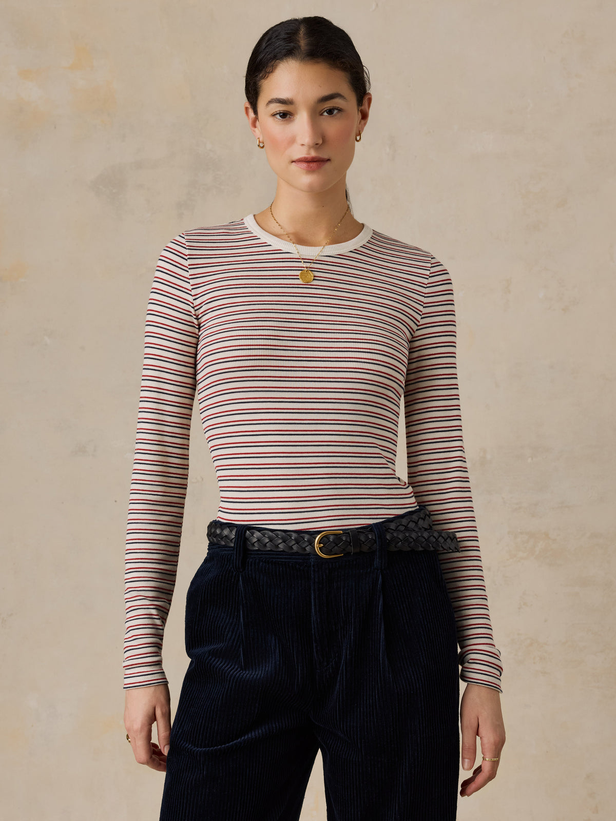 A woman wearing a striped shirt and dark pants, image 1 of 6