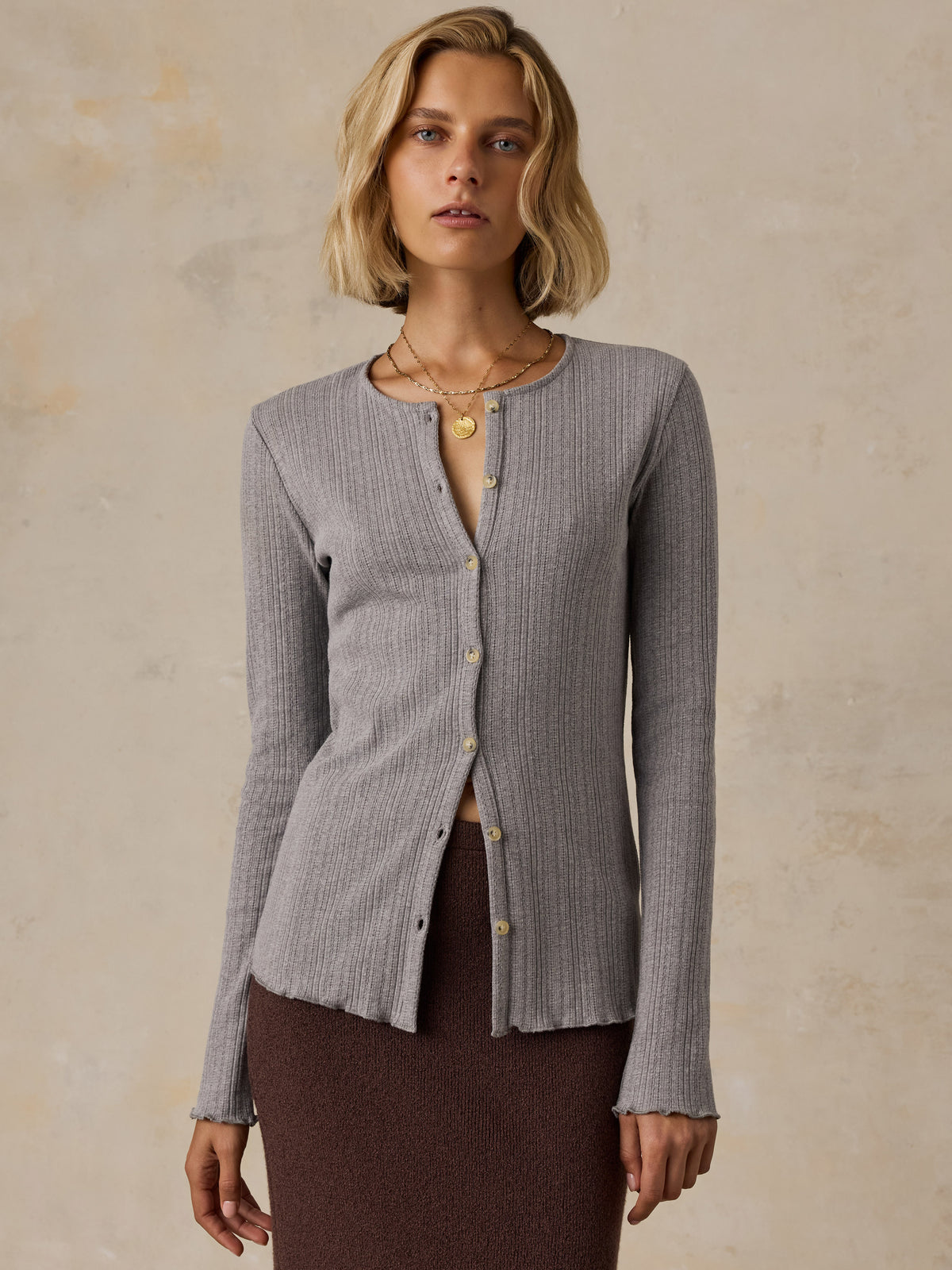A woman wearing a grey cardigan and brown skirt, image 1 of 6