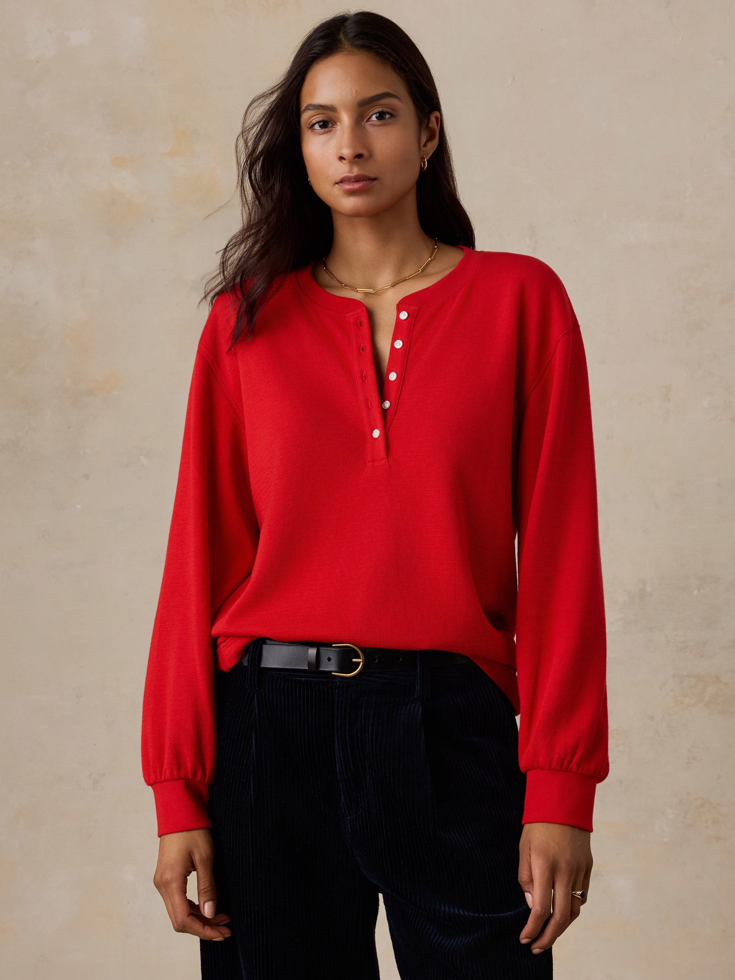 A woman wearing a red henley and dark pants