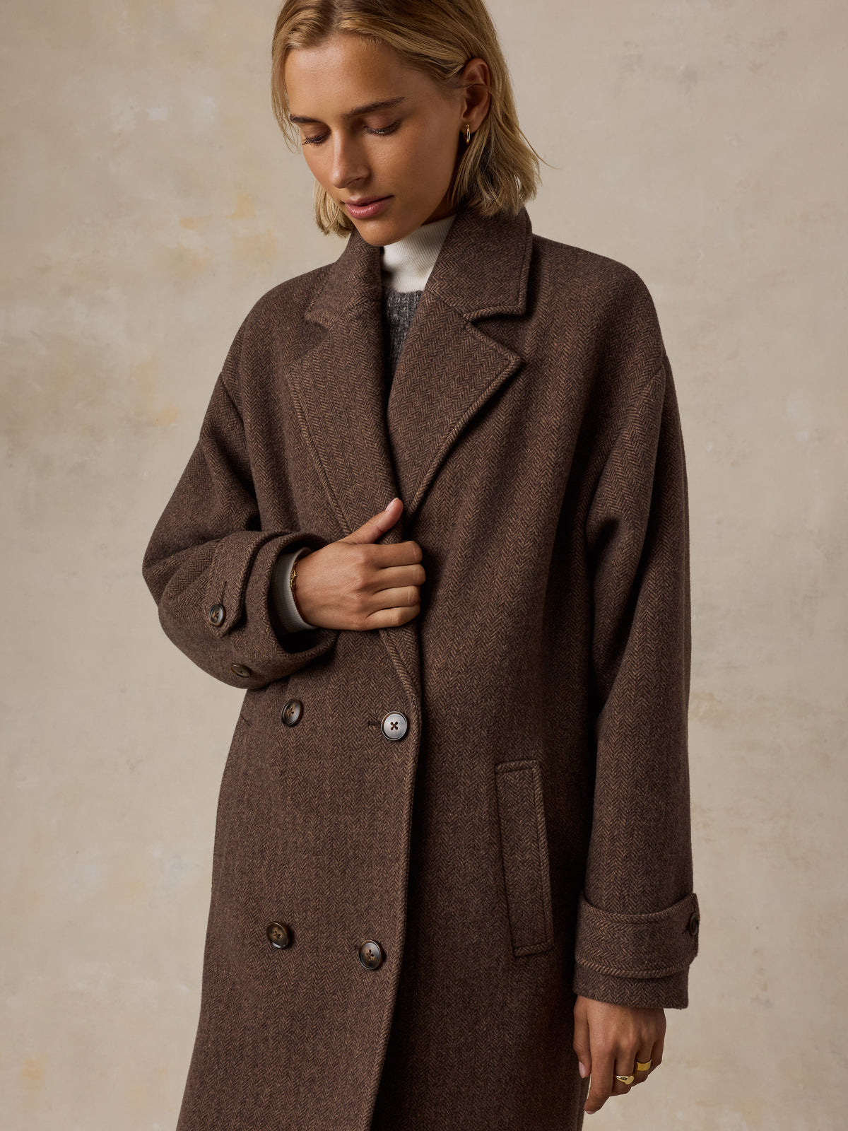 A woman wearing a brown long coat over a sweater , image 9 of 9