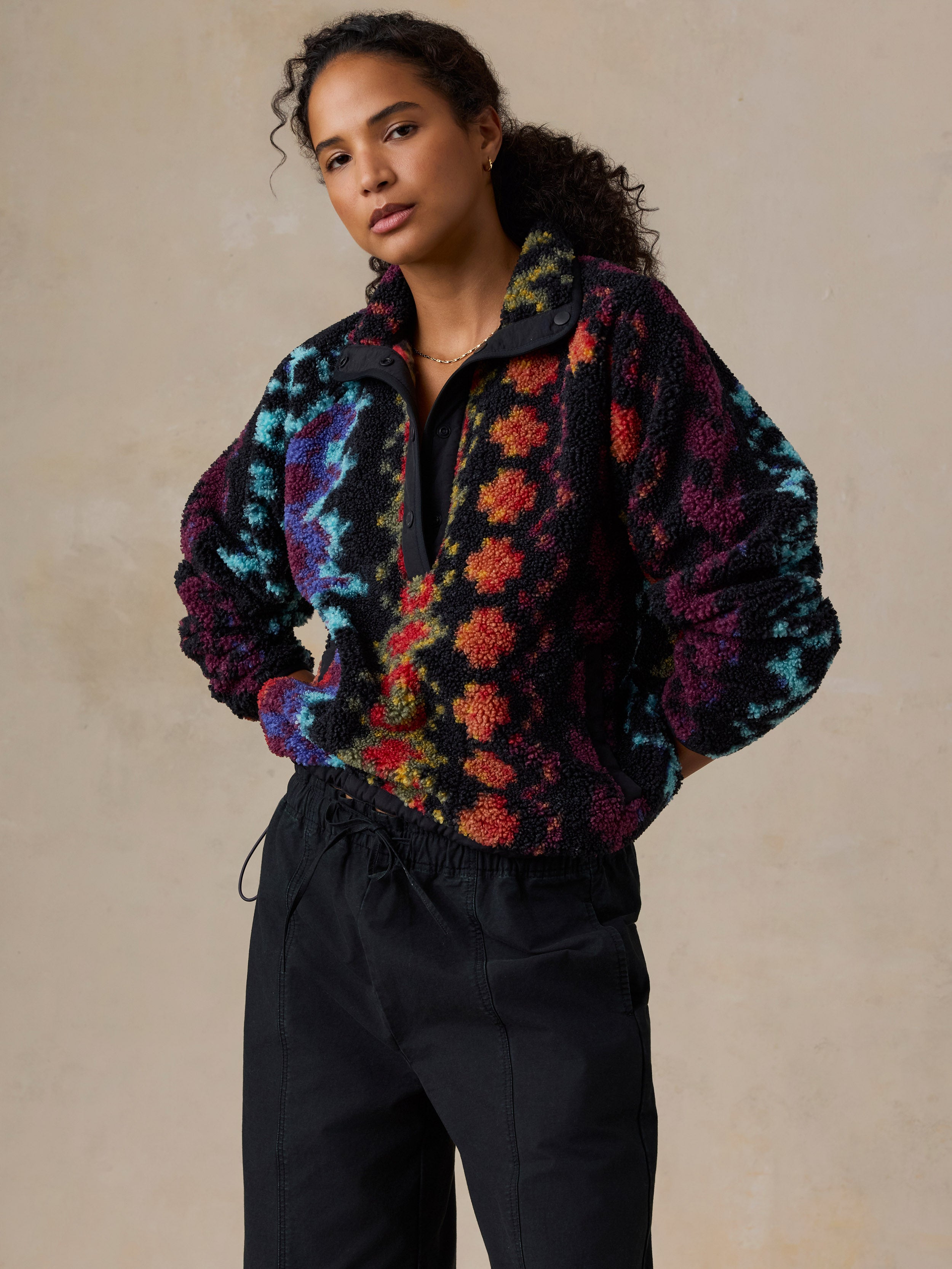 A woman wearing a colorful, patterned fleece pullover and black drawstring pants