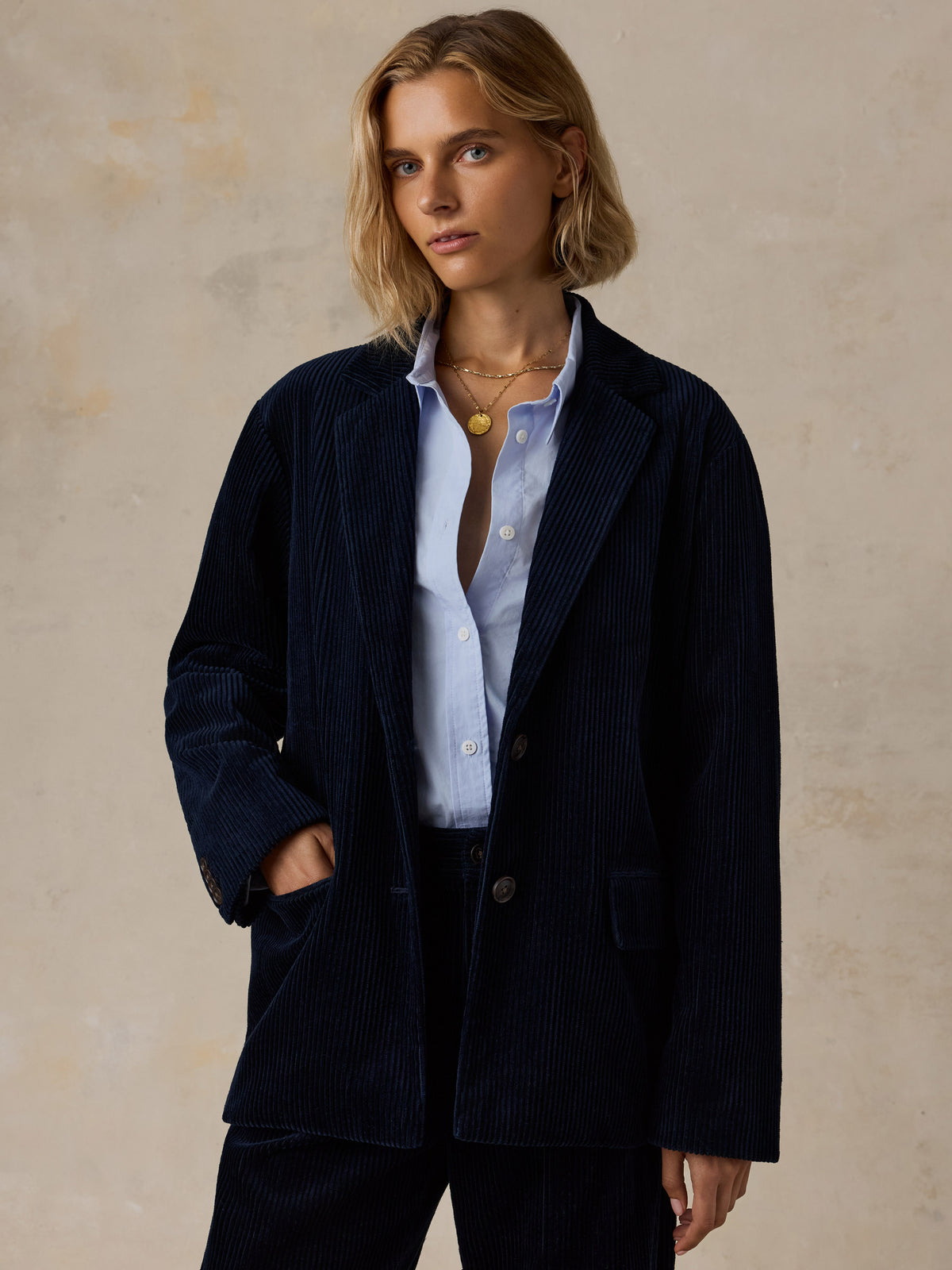 A woman wearing a dark navy blazer over a light blue shirt , image 1 of 7