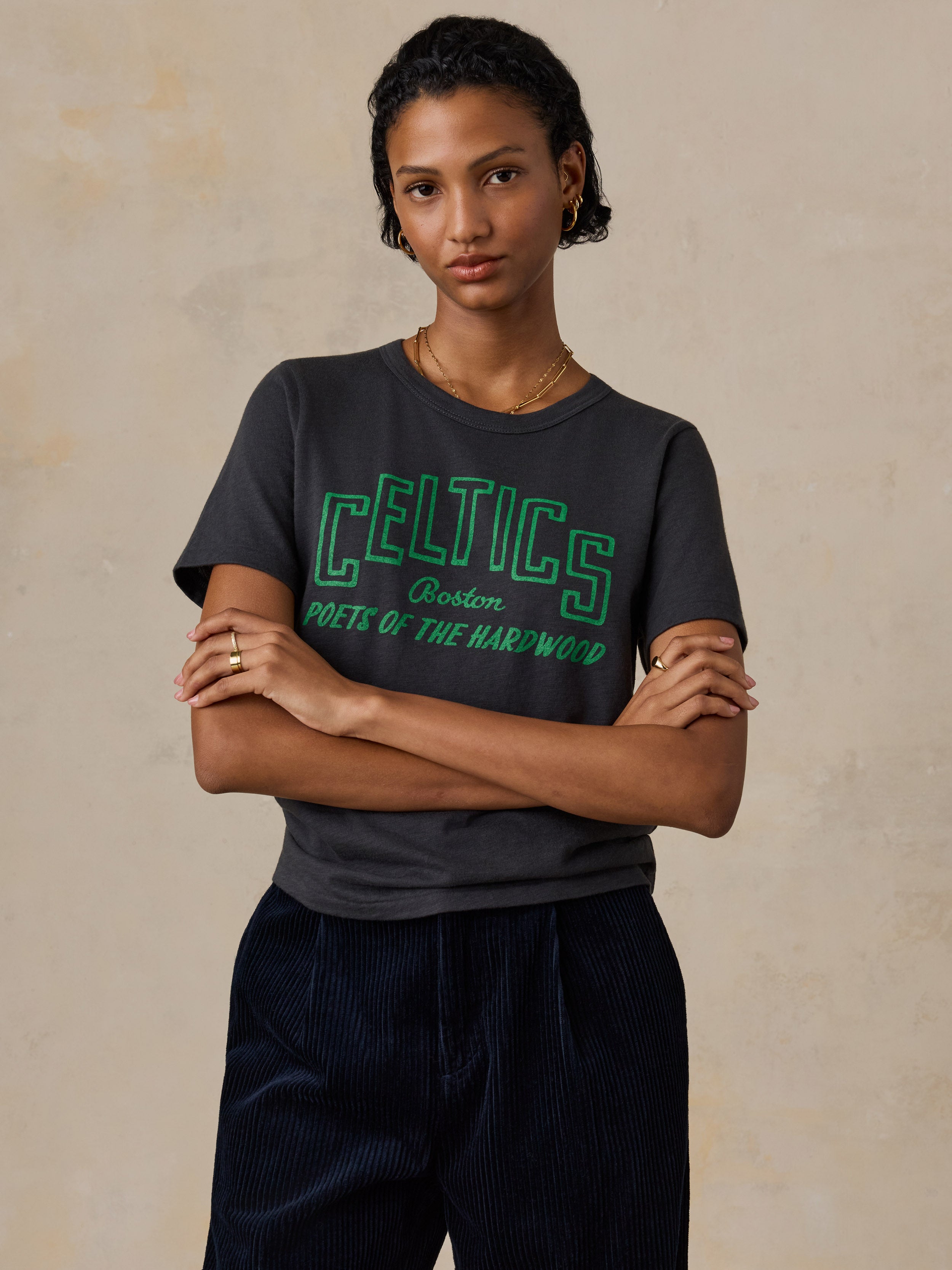 A woman wearing a black Boston Celtics tee and navy pants