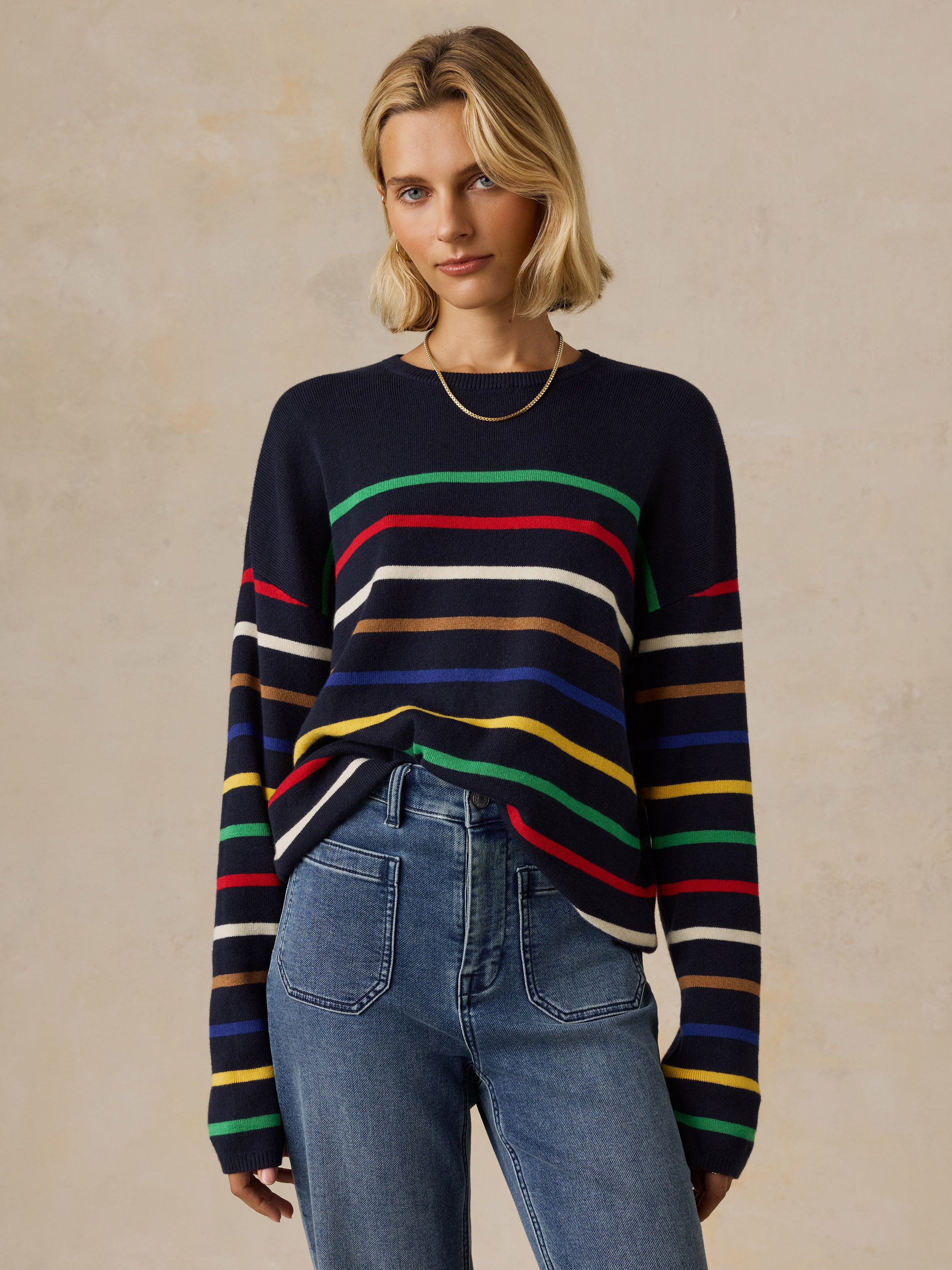 A woman wearing a colorful striped sweater and jeans