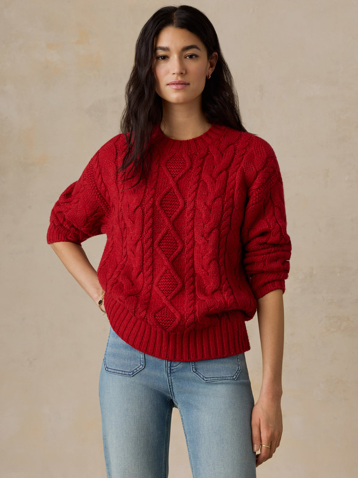 A woman wearing a red sweater and jeans, image 3 of 5