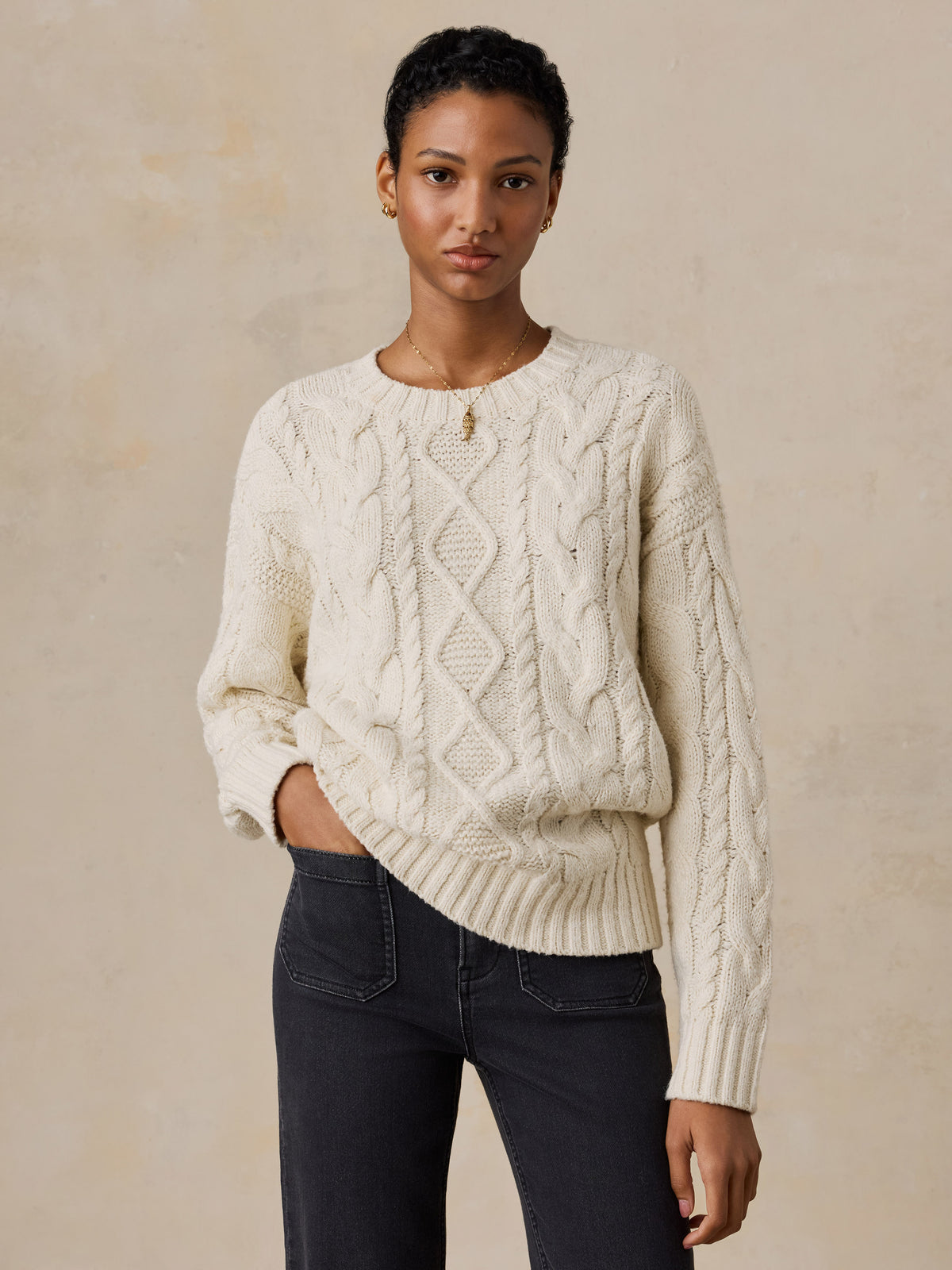 A woman wearing a white sweater and black jeans, image 1 of 5