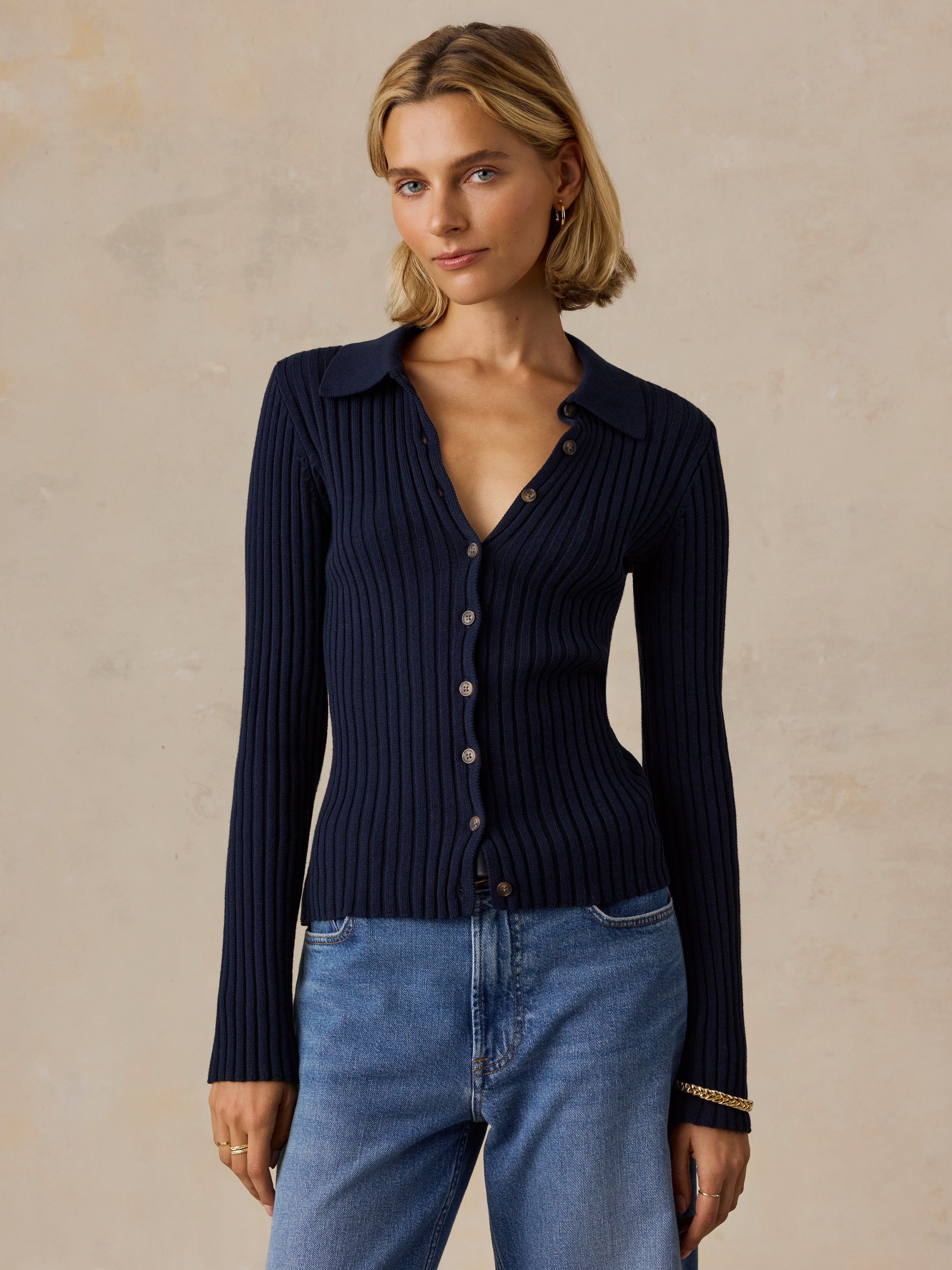 A woman wearing a blue cardigan and jeans