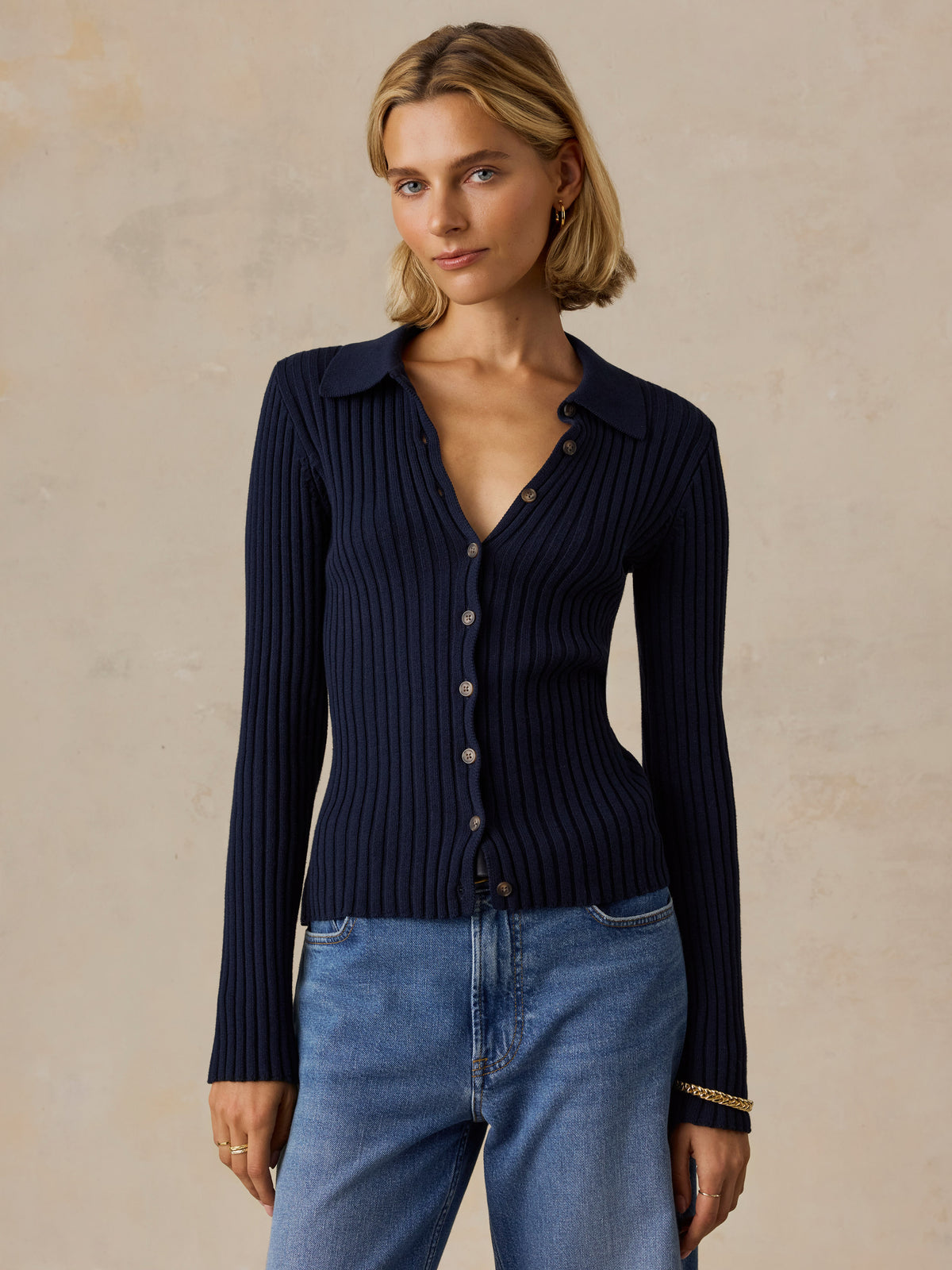 A woman wearing a blue cardigan and jeans, image 1 of 5