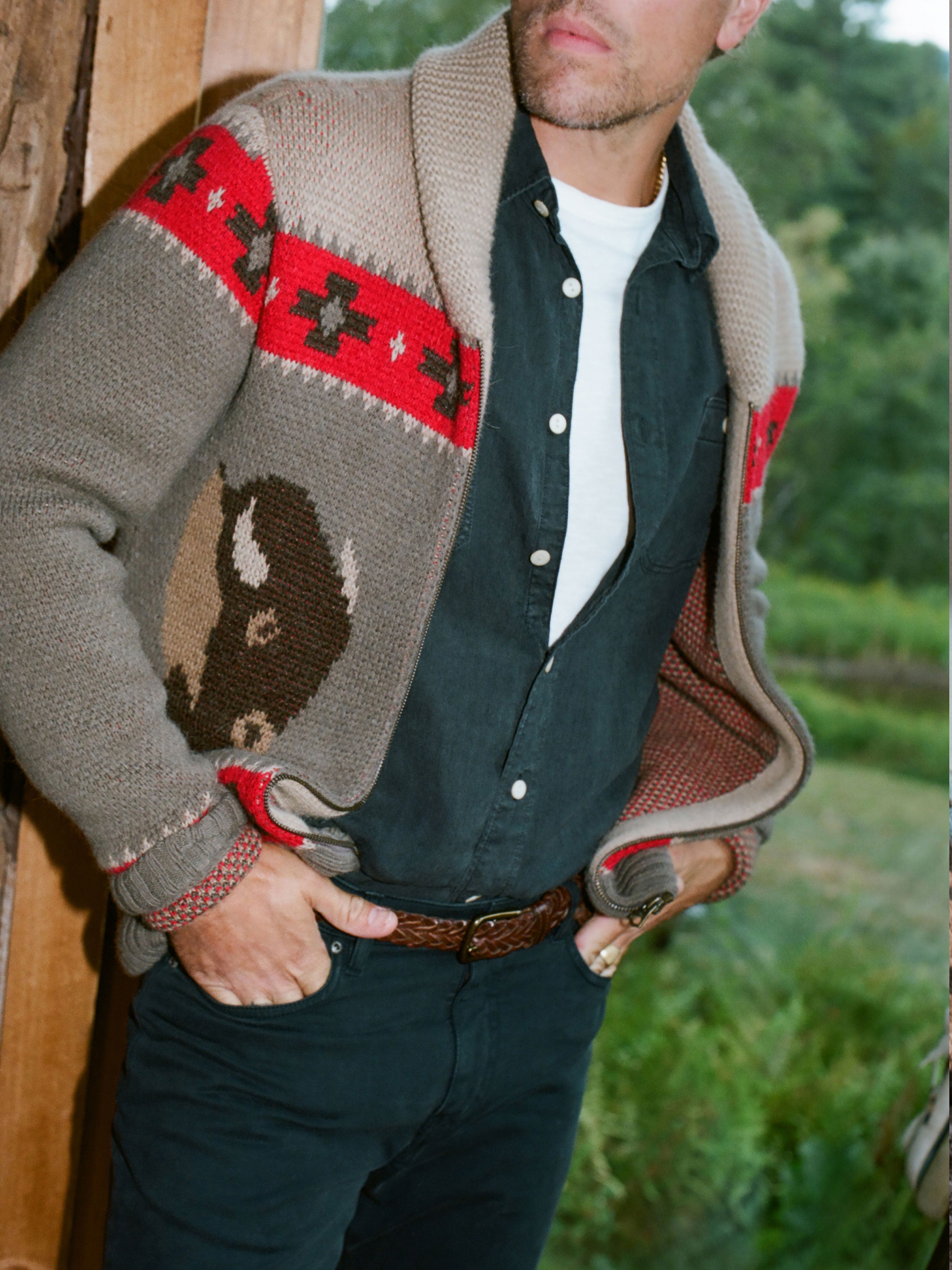 Man wearing a patterned cardigan with a buffalo design outdoors