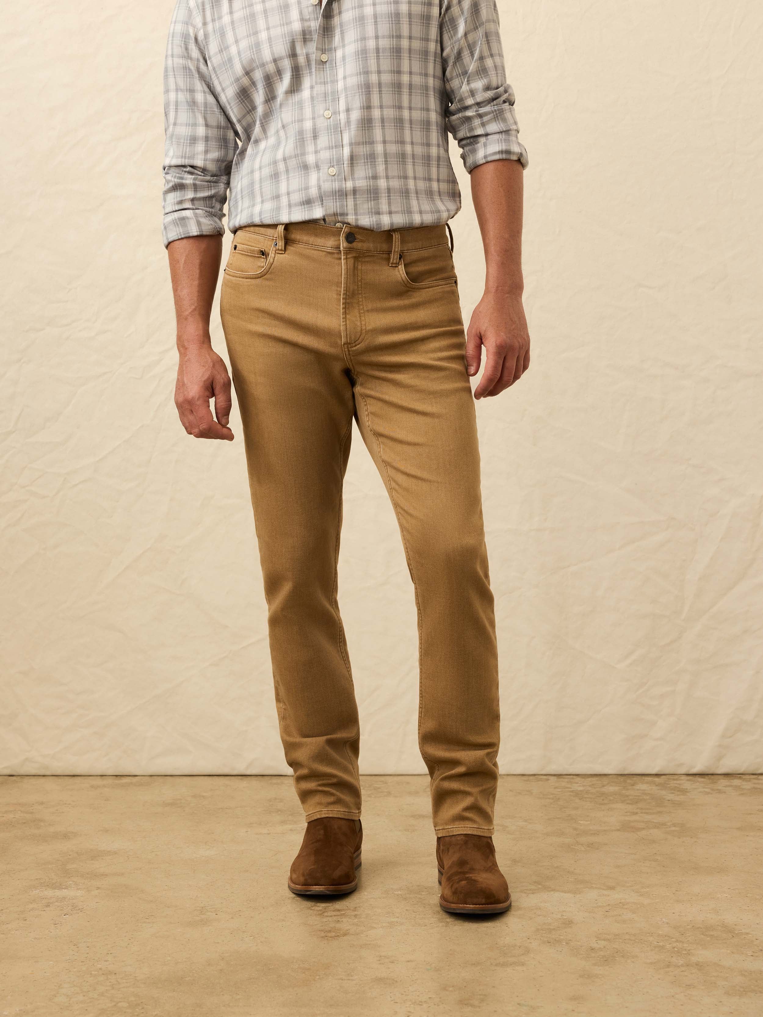 Man wearing a plaid shirt, light brown pants, and brown shoes against a beige background