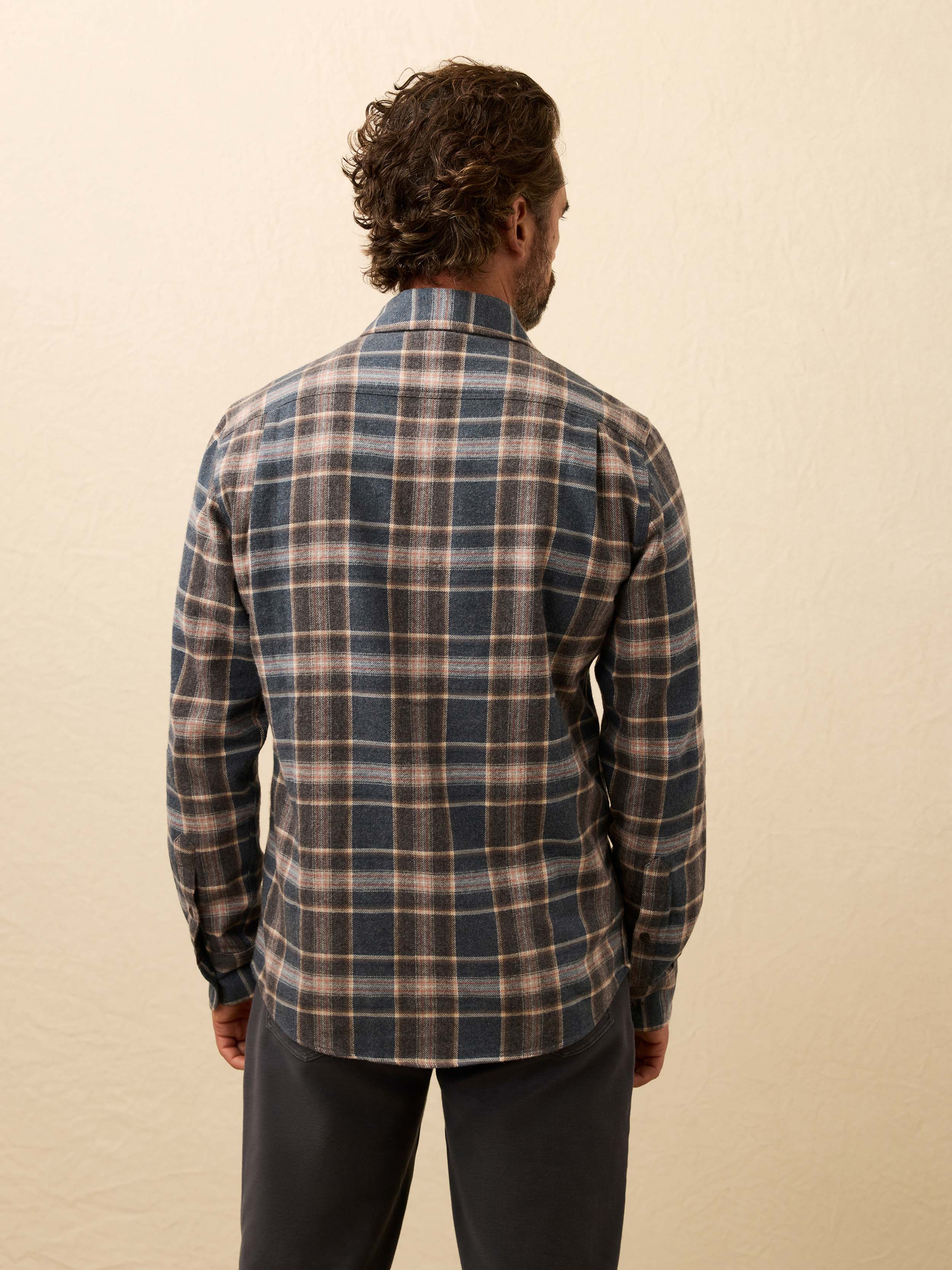 Man wearing a plaid shirt against a beige background