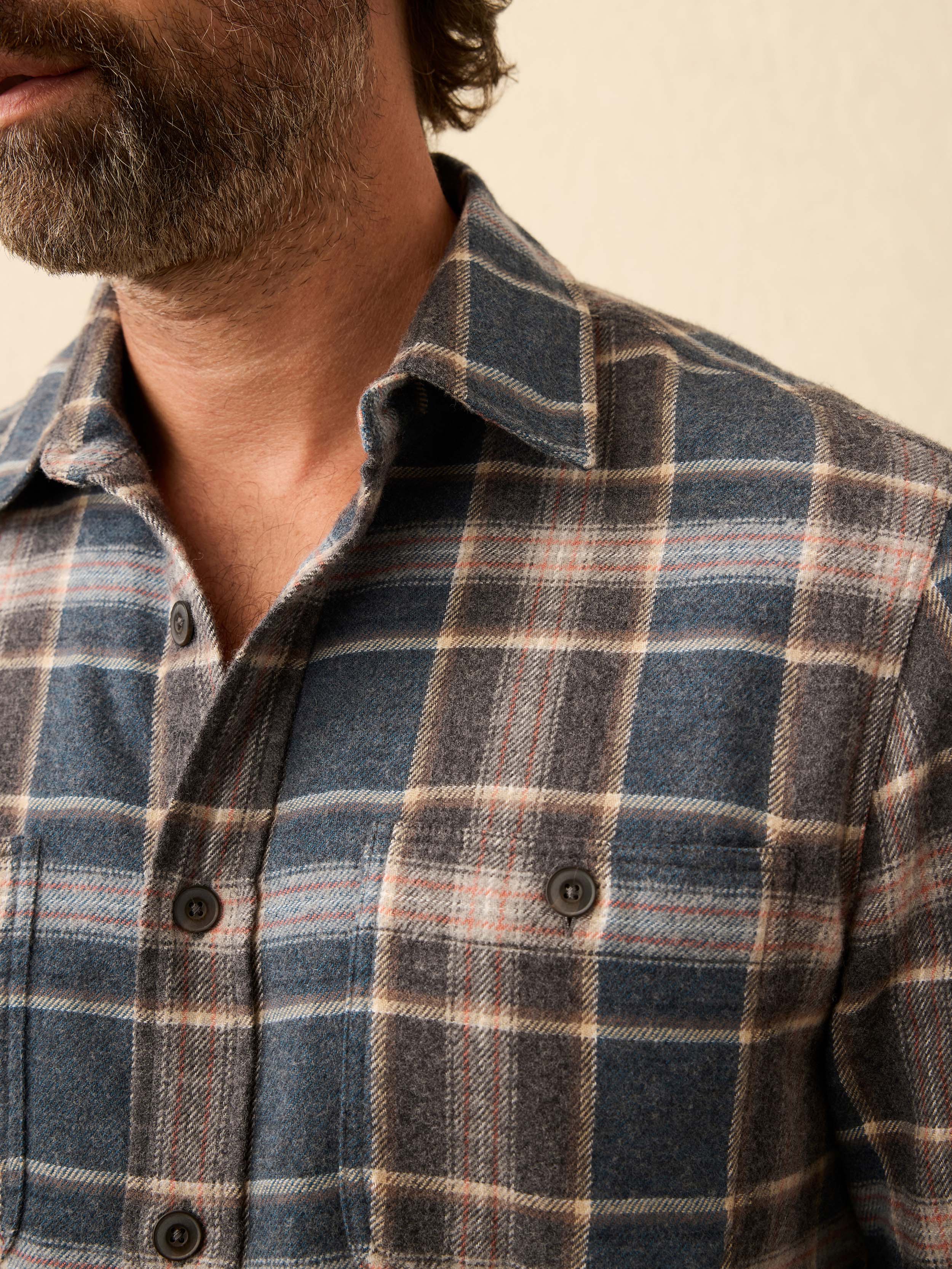 Close-up of a person wearing a plaid shirt with a neutral background