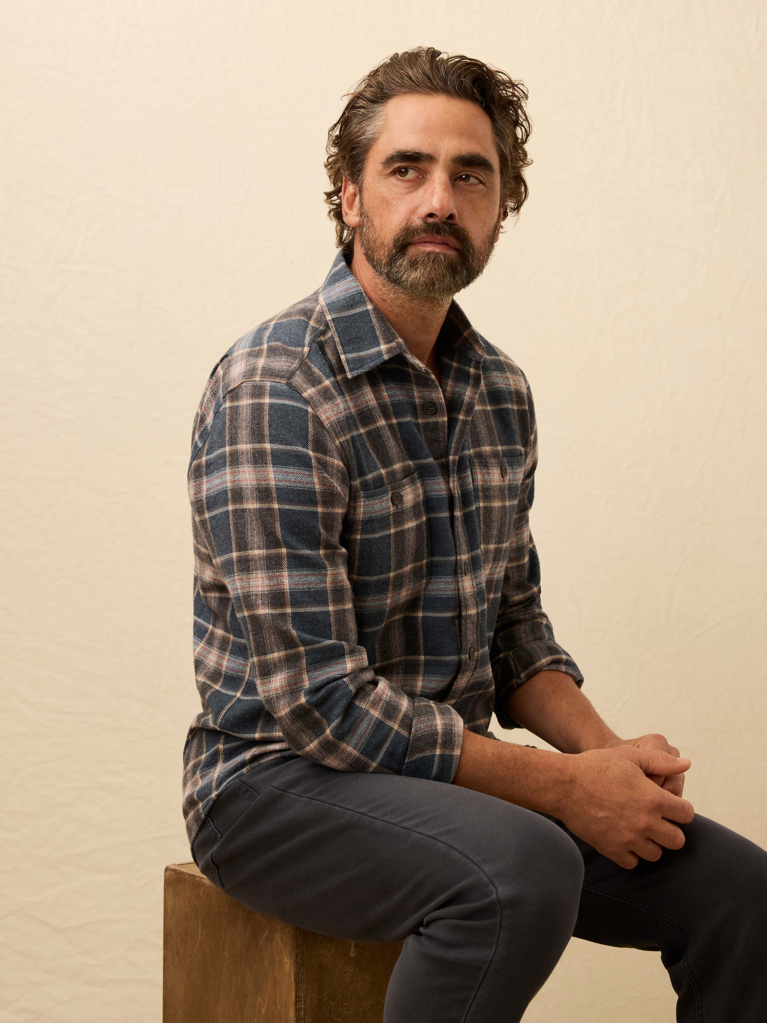 Man wearing a plaid shirt against a beige background