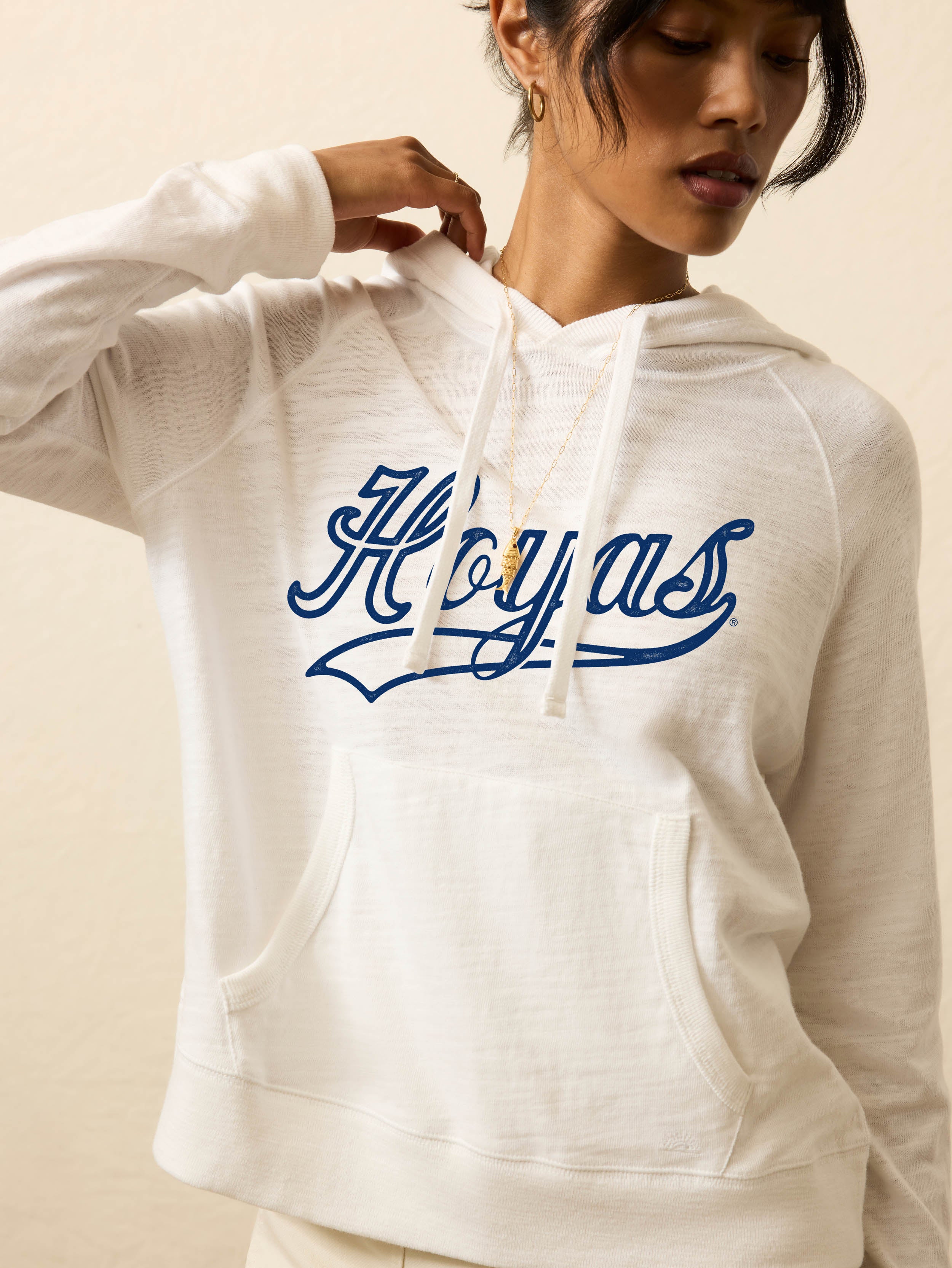 Woman is wearing a heather grey hoodie with Georgetown graphic on the front against a beige background