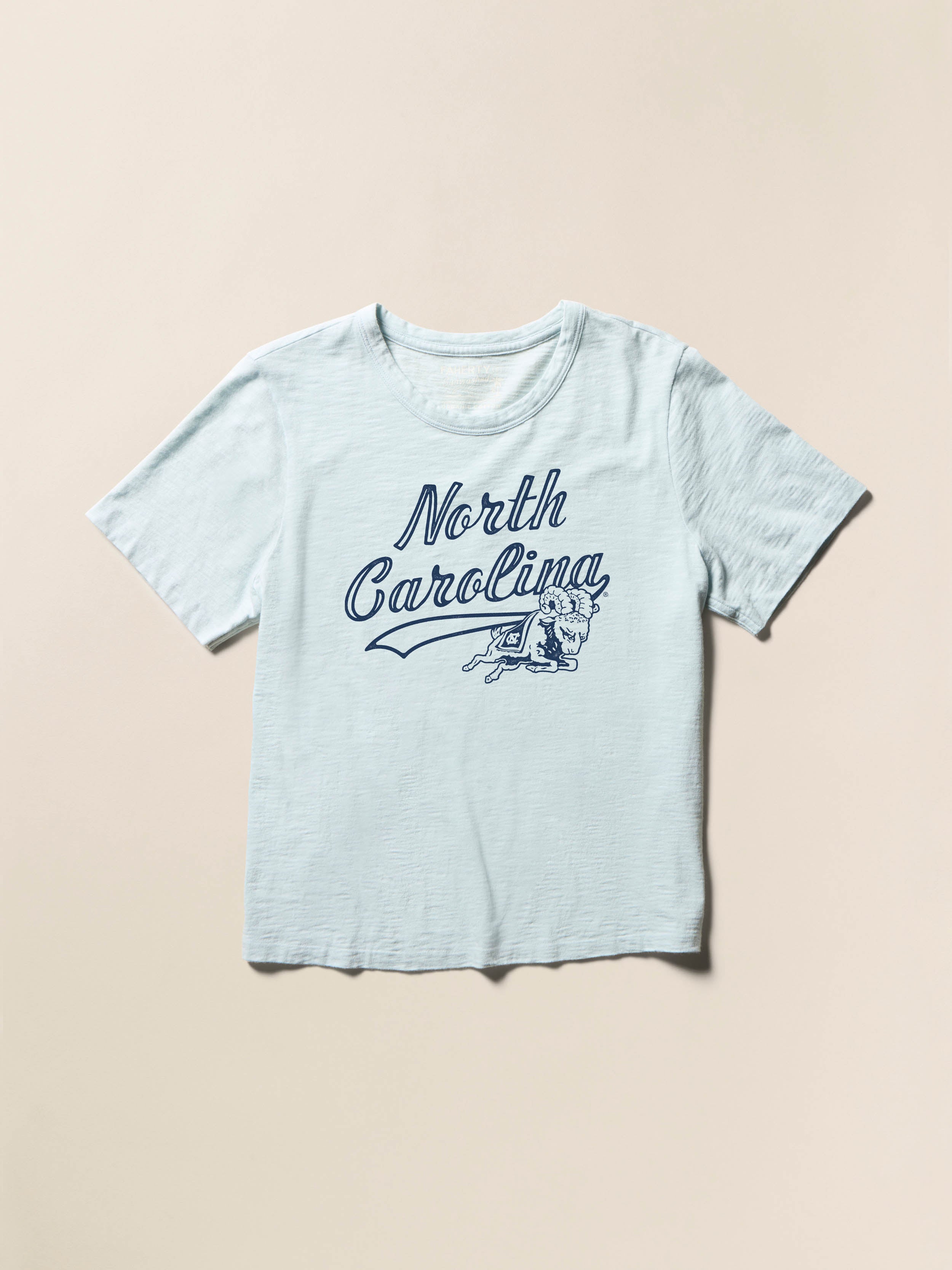 Light blue short sleeve t-shirt with UNC graphic on the center chest against a beige background