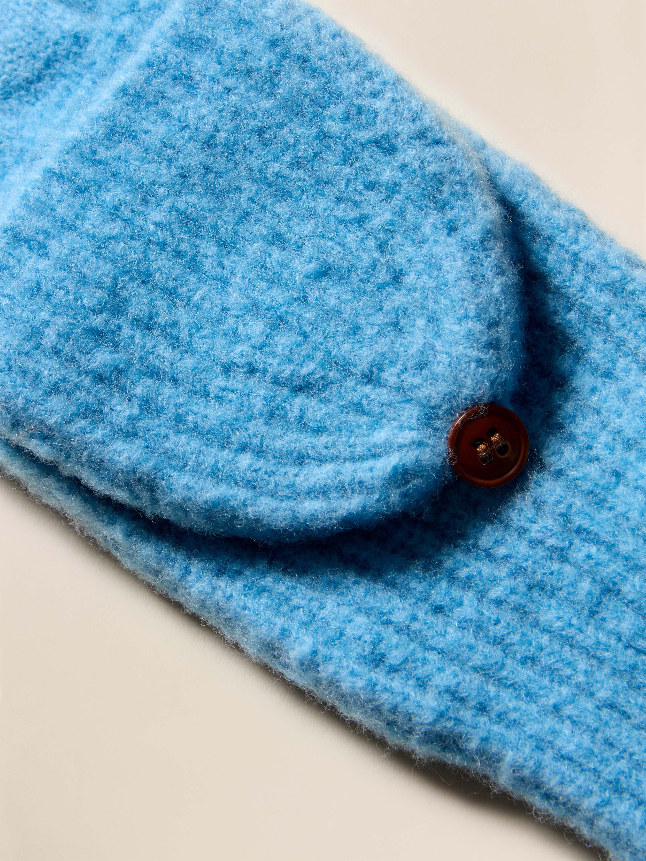 Close-up of blue knit gloves with a button on a beige background