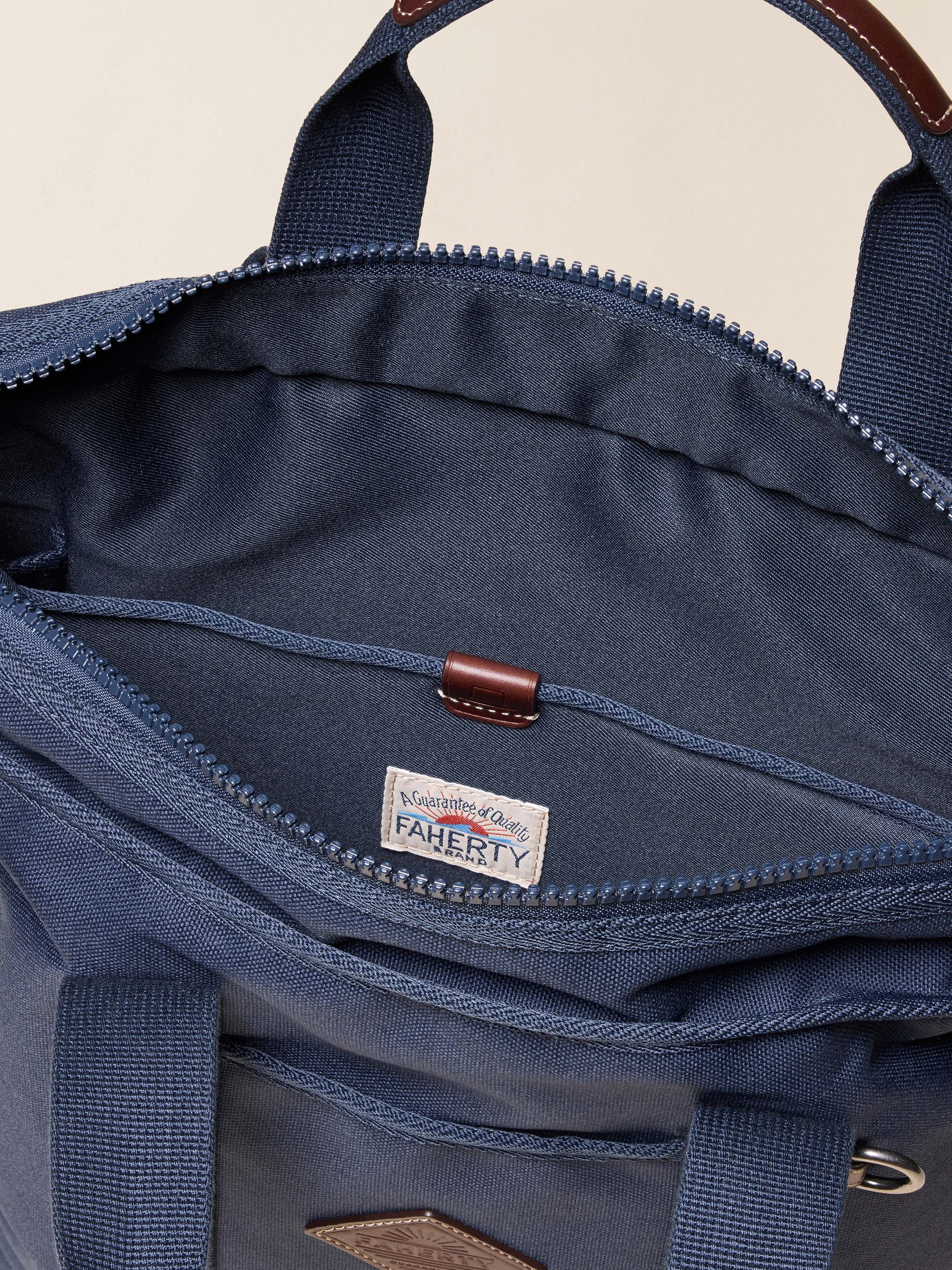 Close-up of a blue backpack with a Faherty brand label on a beige background