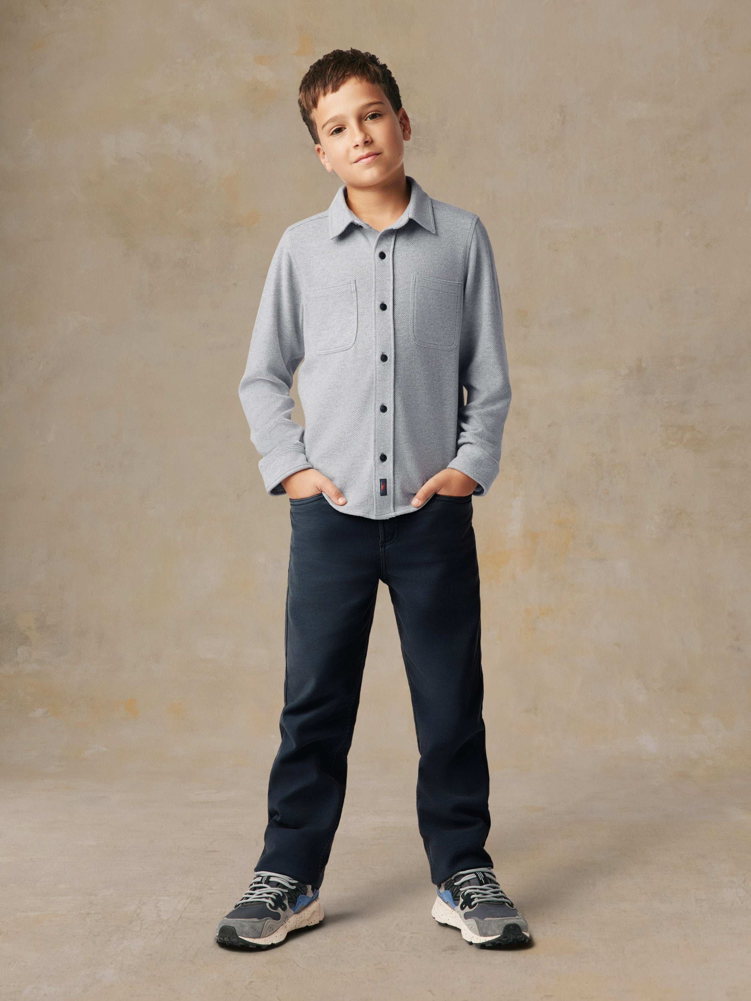 A child wearing a grey button up shirt and black pants