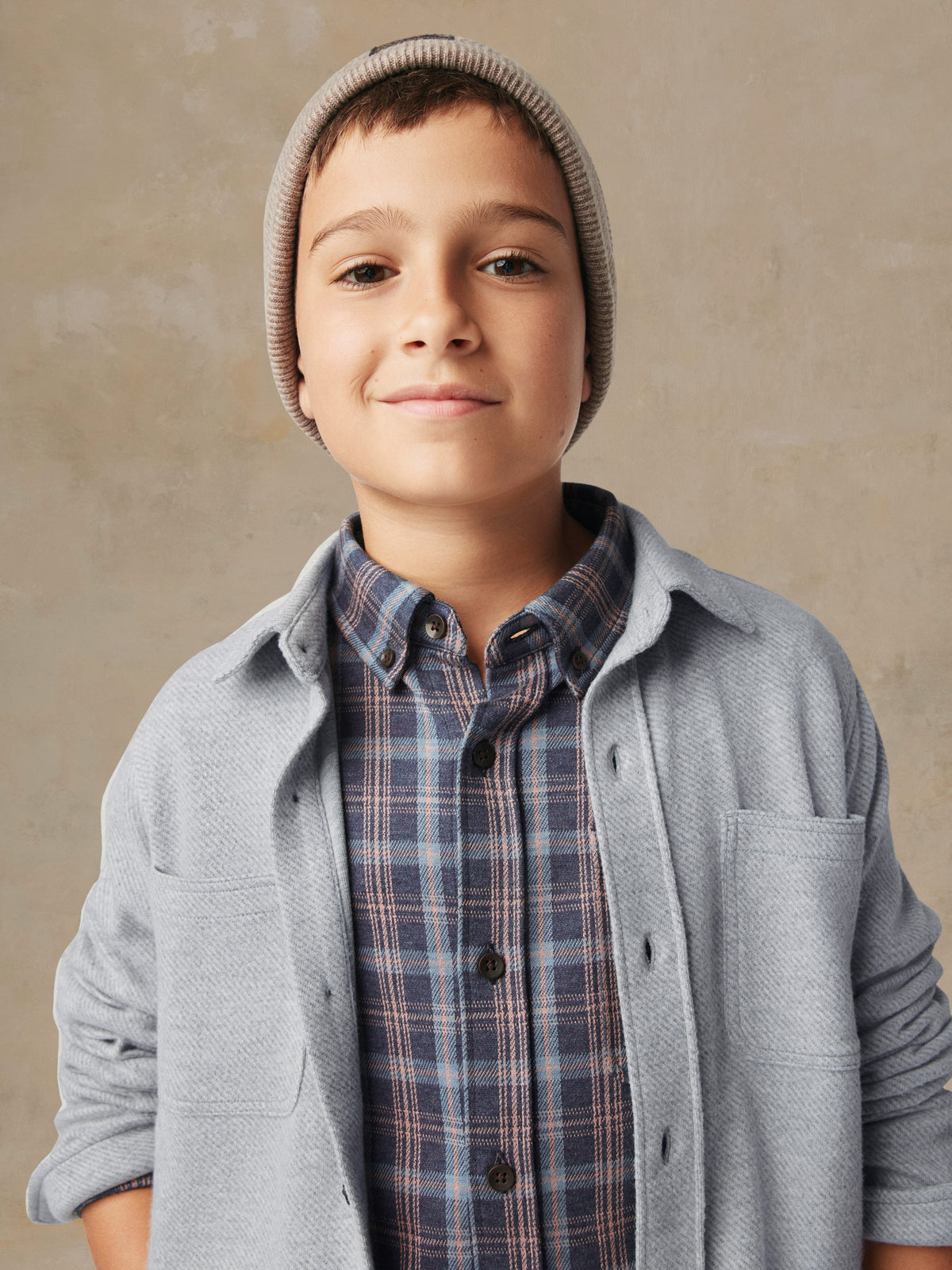 Close up of a child wearing a grey button up shirt over a plaid shirt, image 4 of 7