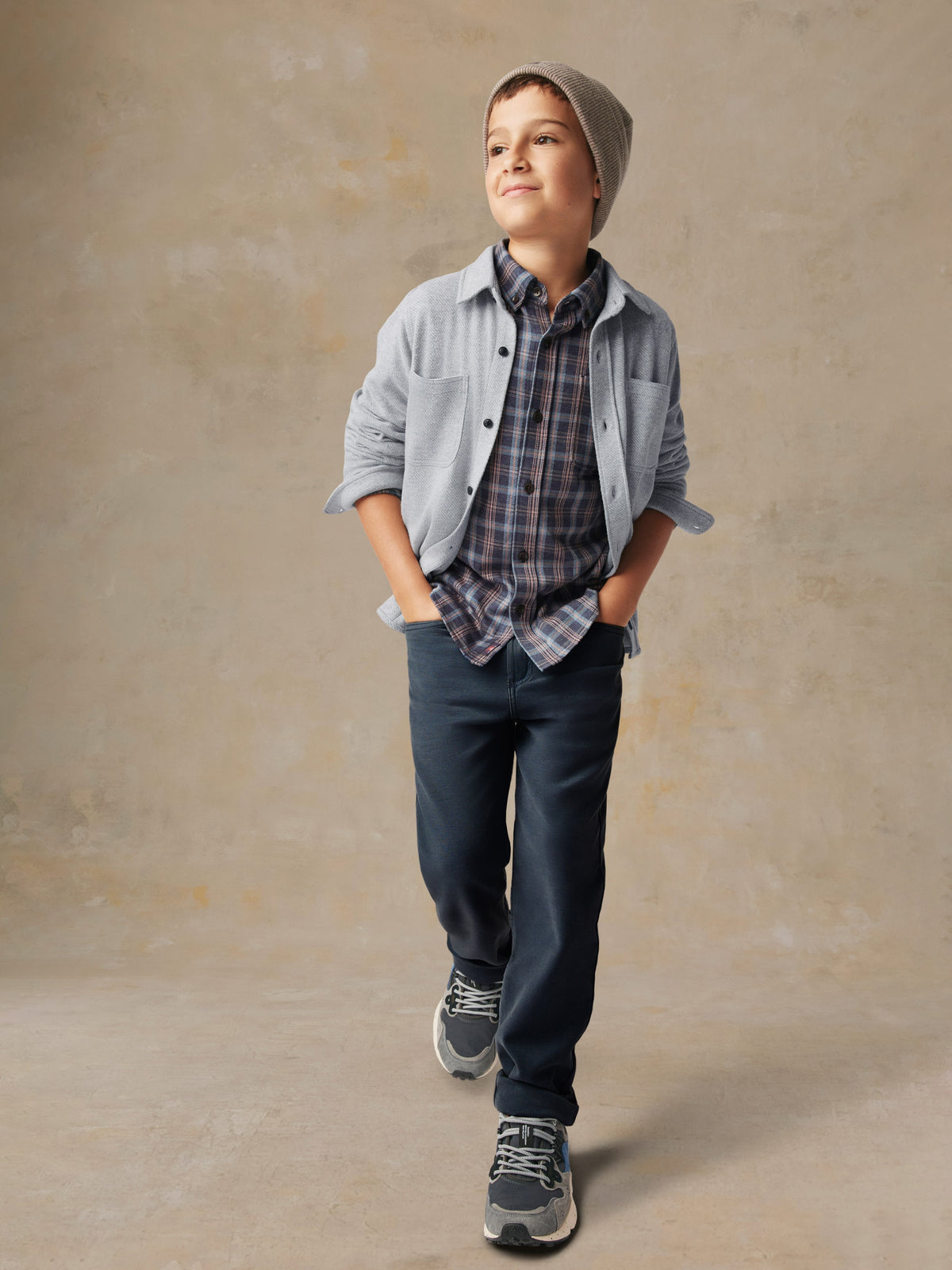 A child wearing a grey button up shirt and black pants, image 6 of 7