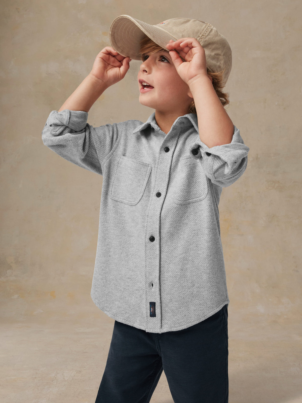 Close up of a child wearing a grey button up shirt and black pants, image 2 of 6