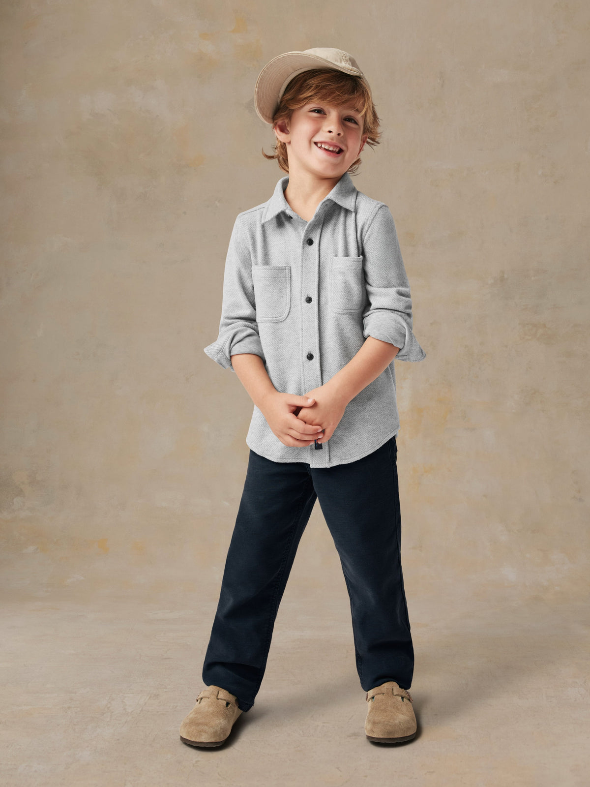 A child wearing a grey button up shirt and black pants, image 4 of 6