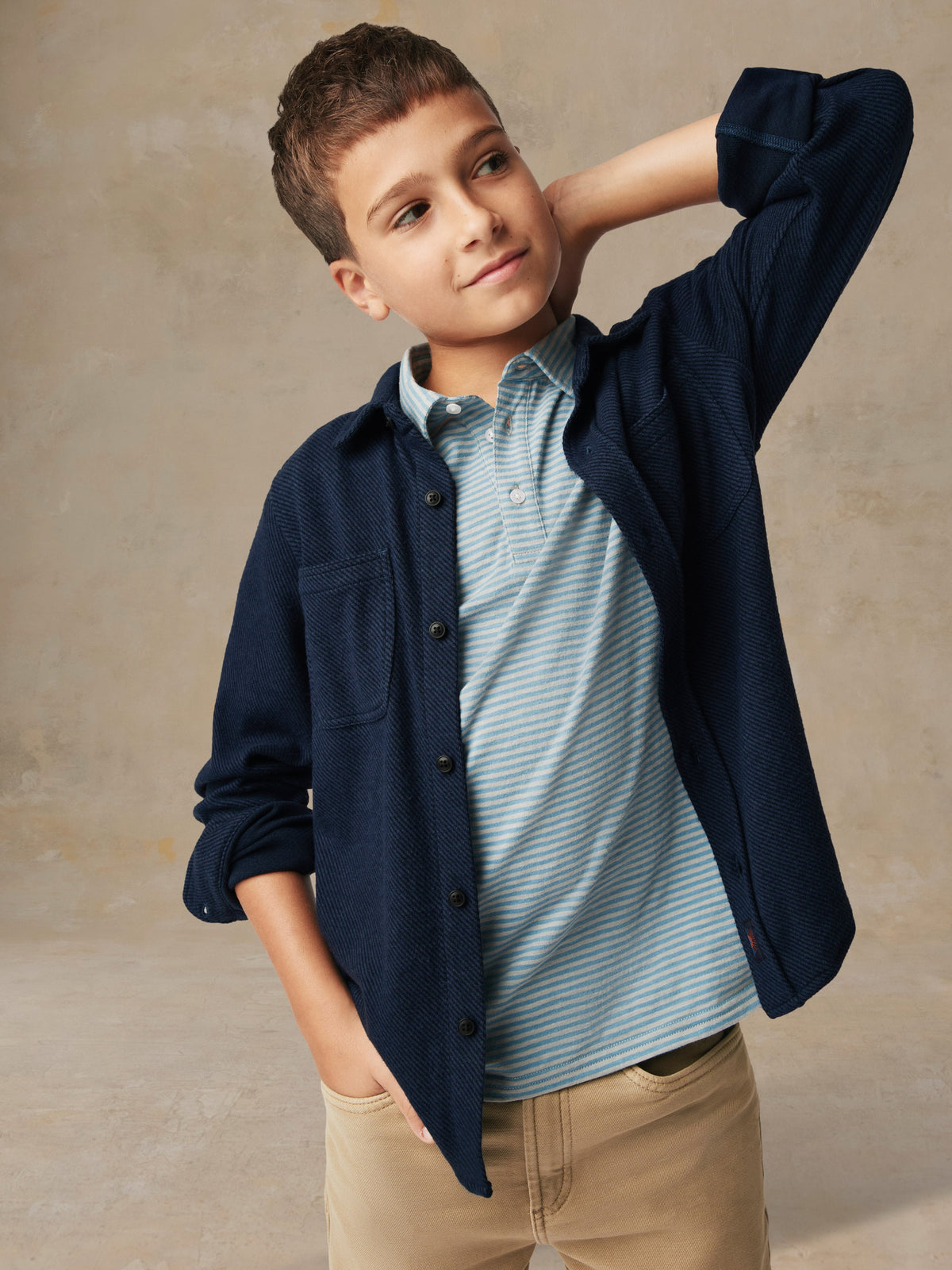 Close up of a child wearing a blue button up shirt and beige pants, image 2 of 6