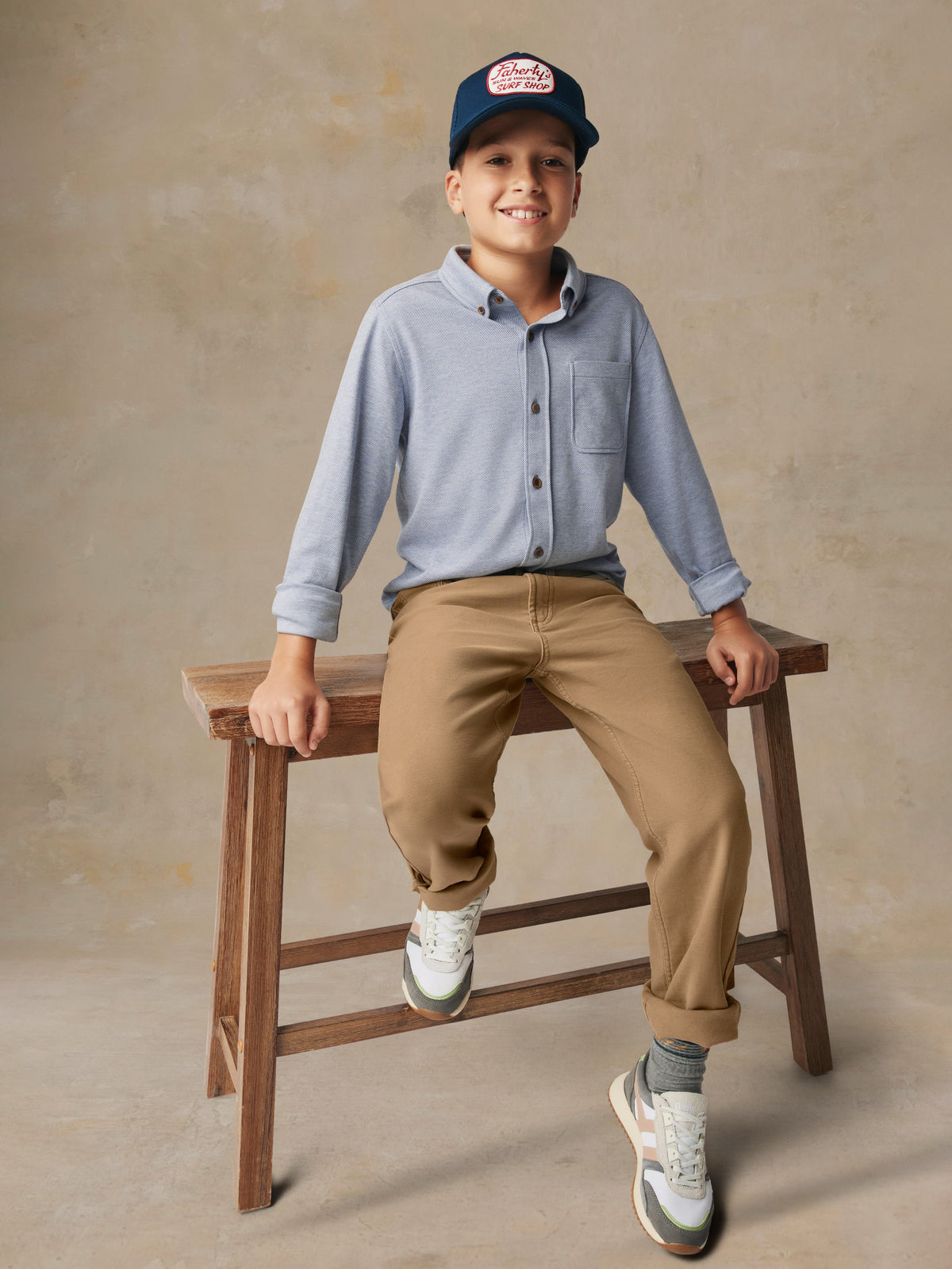 A child wearing a blue button up shirt and beige pants, image 4 of 7