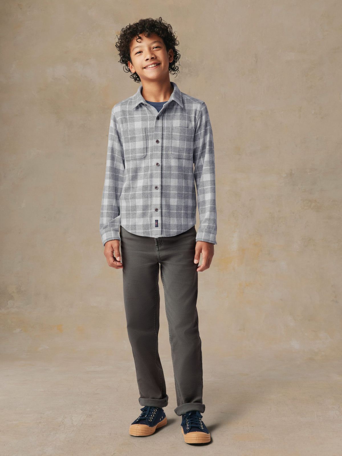 A child wearing a grey plaid button up shirt and grey pants, image 2 of 7